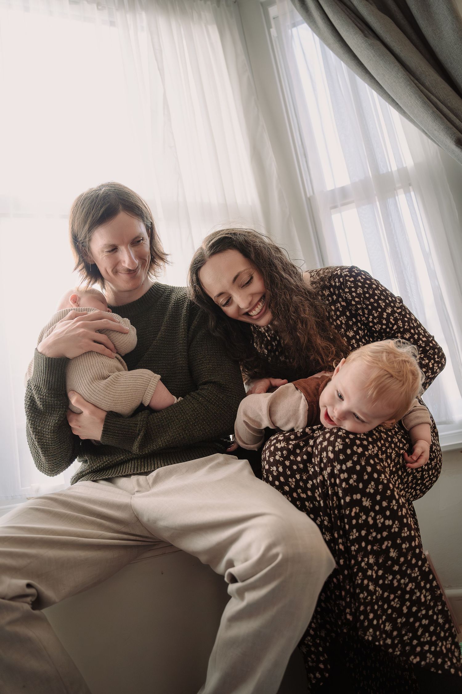 A heartwarming family moment by a window with matching polka dot and knit sweater outfits.