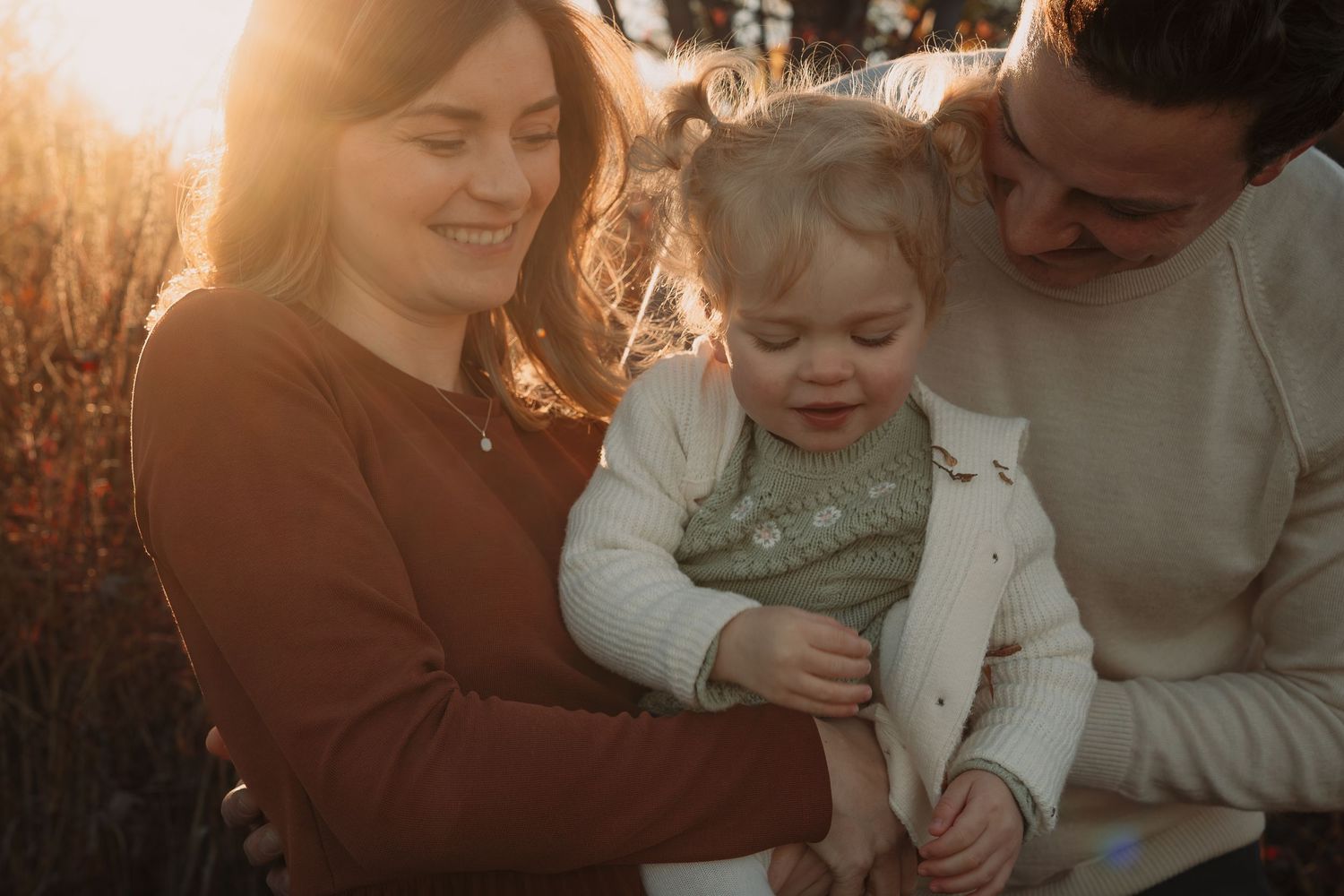 Family sharing tender moments during golden hour sunset outdoors.