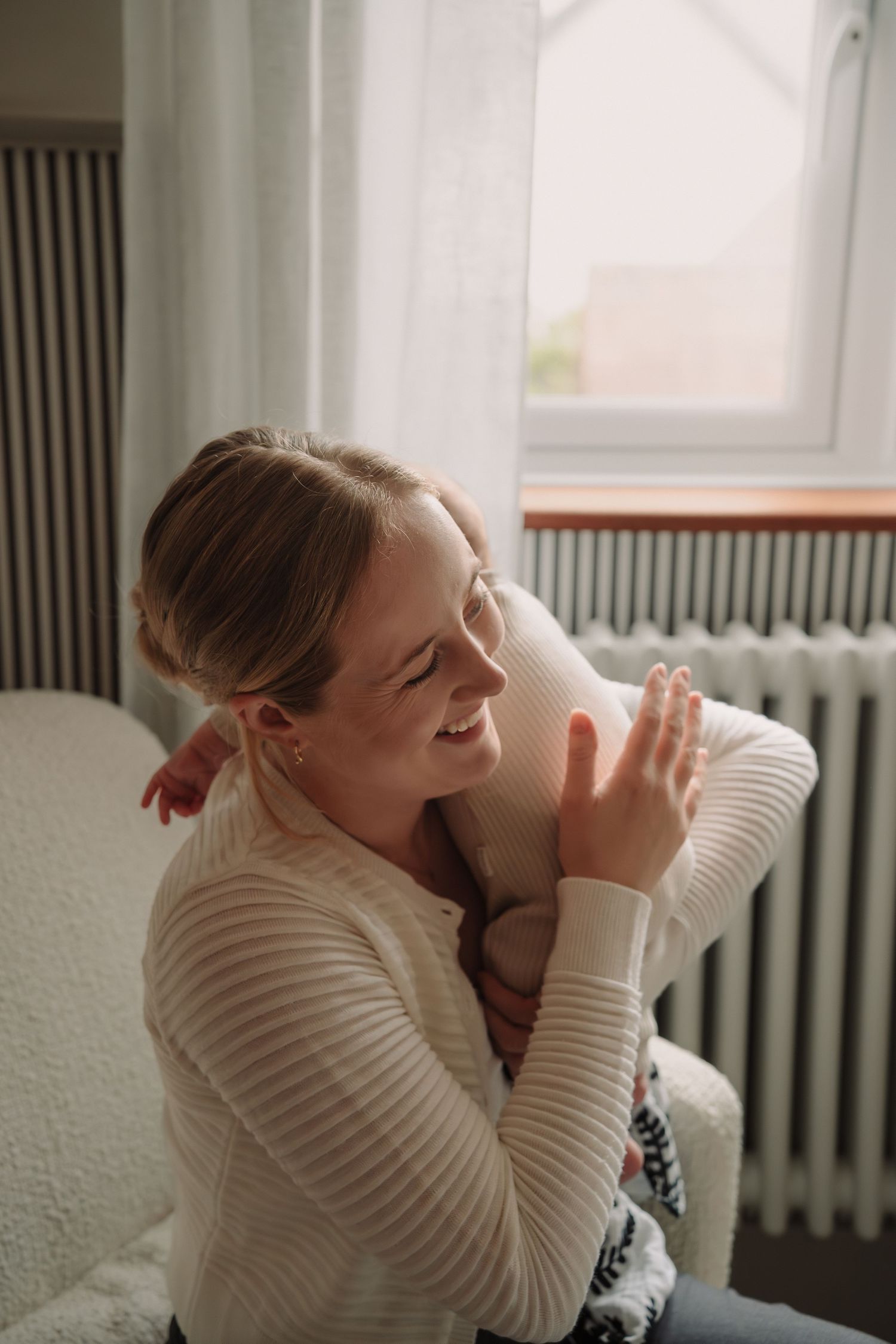 A person in a cream sweater sits by a window and drinks from a white mug in a series of four photos.