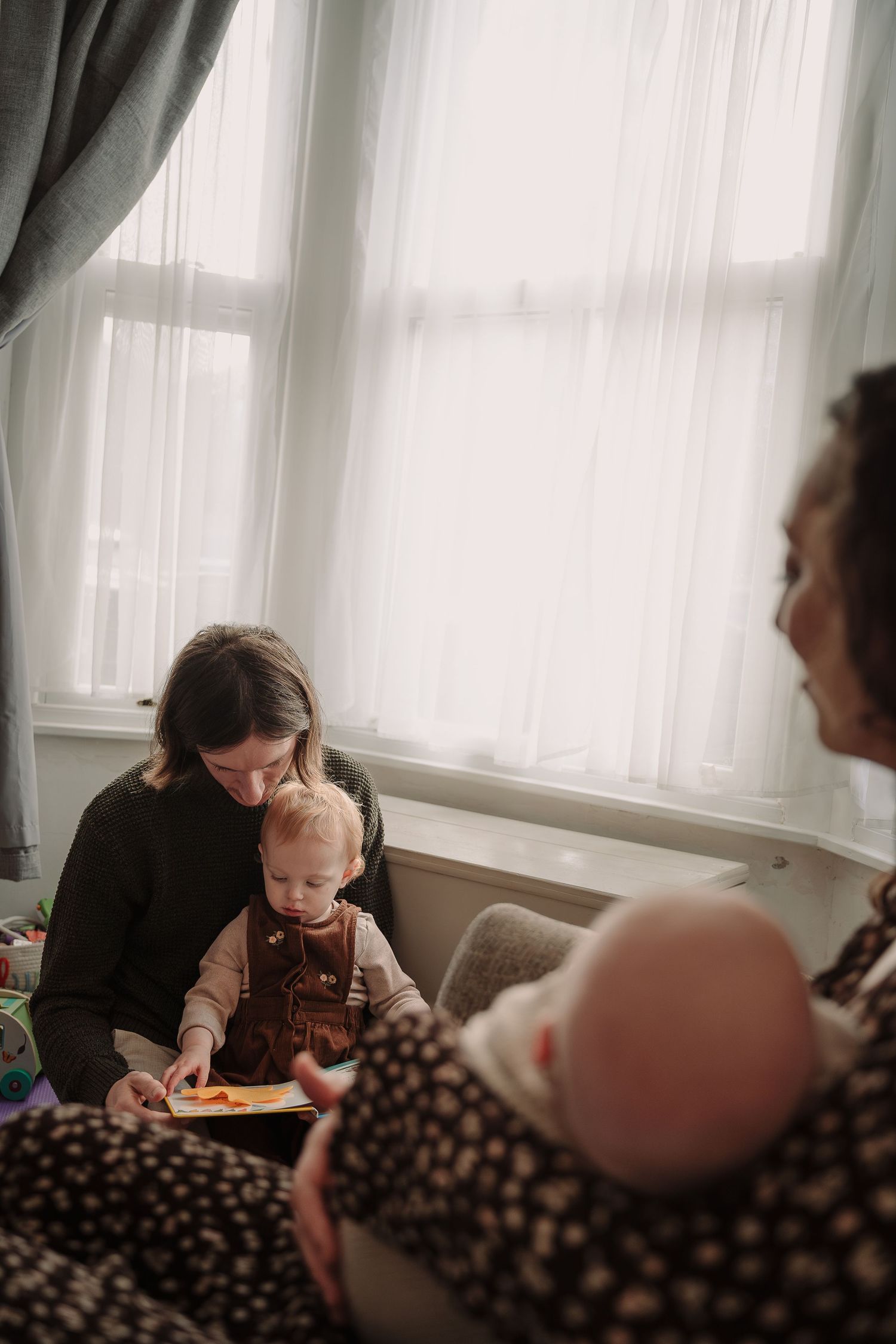 A cozy indoor scene showing people reading and spending time together by a window.