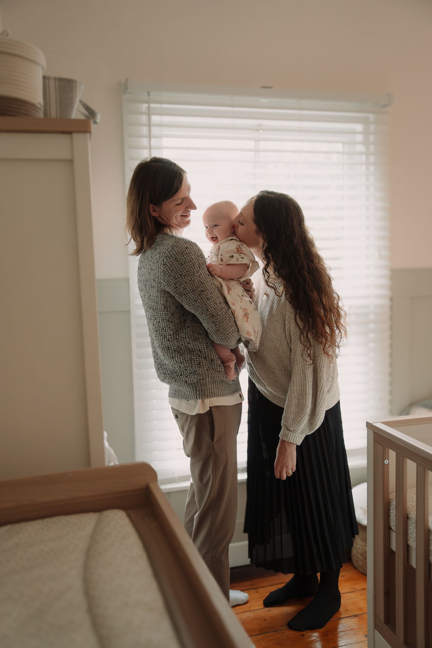 A series of candid lifestyle photos showing tender family moments in a sunlit room by a window.