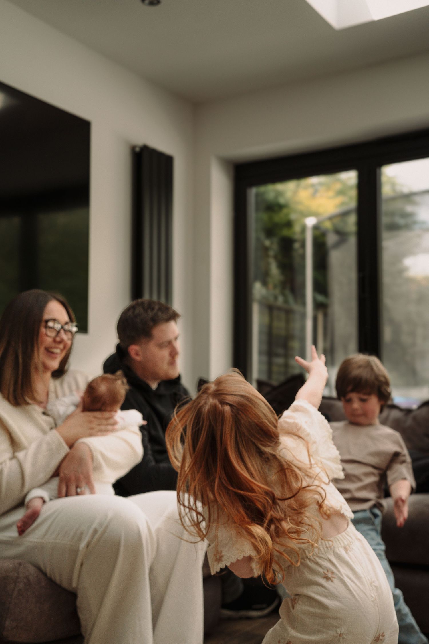 A sequence of candid family photos showing joyful playtime and laughter in a bright living room.
