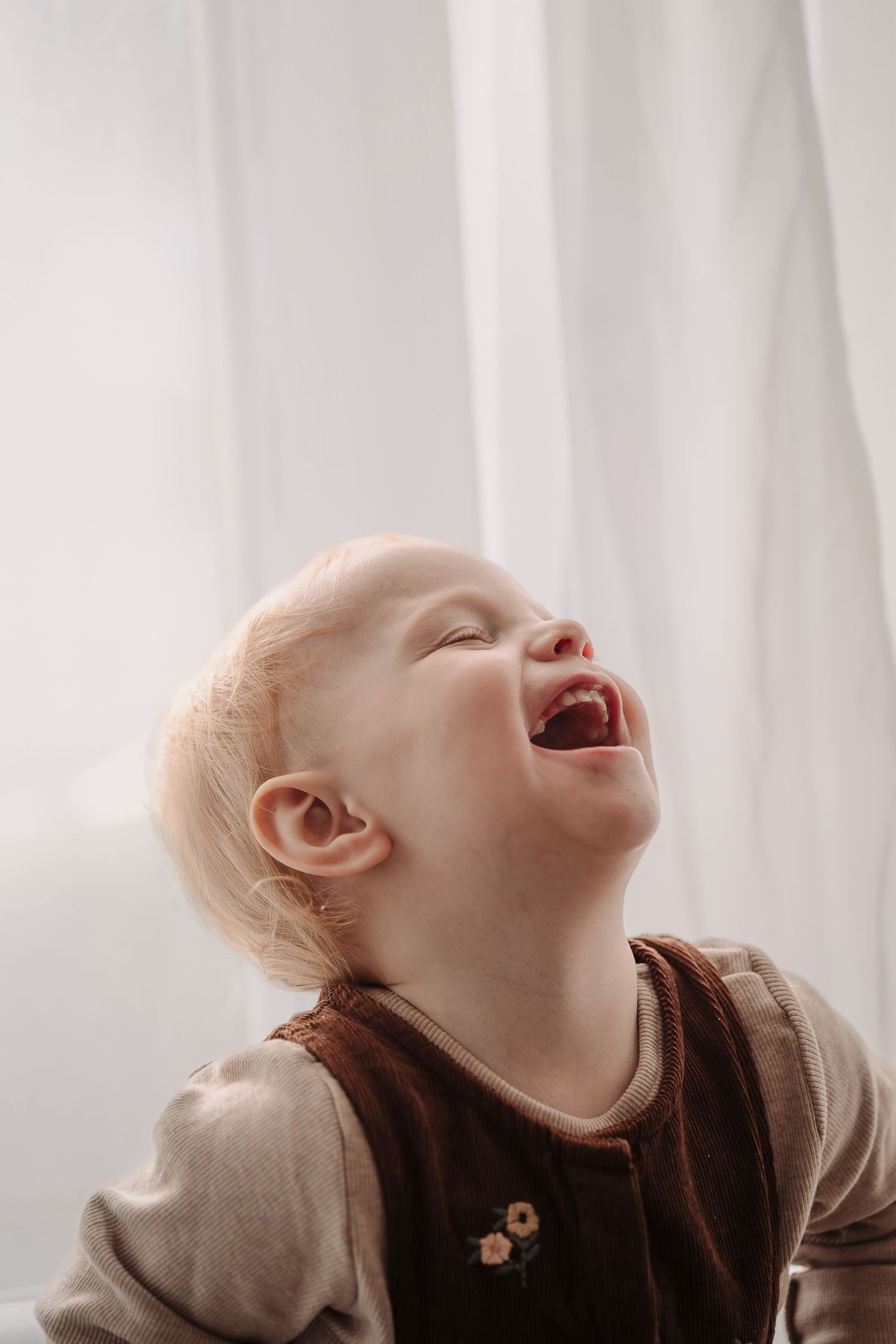 Series showing a baby's delighted laughter against bright window light and white curtains.