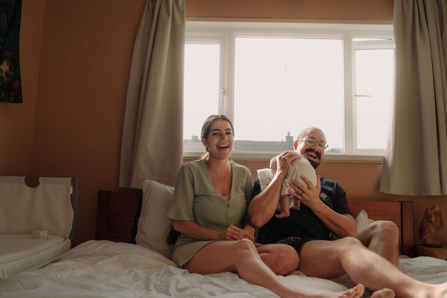 Two people relax together while reading in bed on a sunny morning.