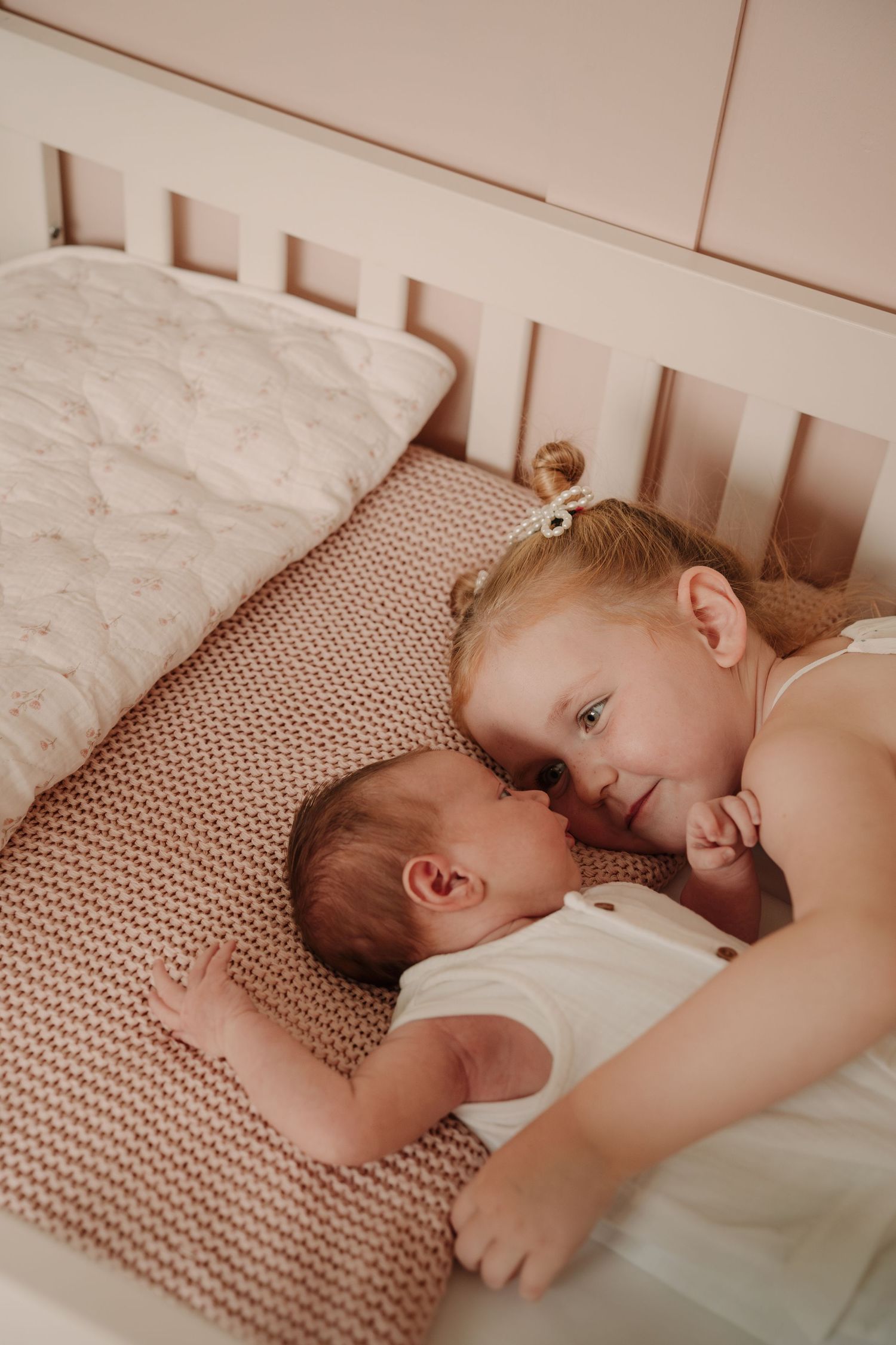 Children sharing a quiet moment together on a textured bedspread.