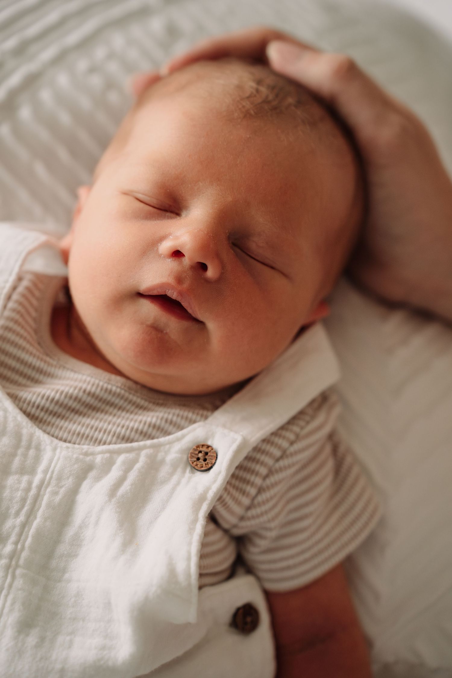 Close-up shots of sleeping newborn in striped and white clothing.