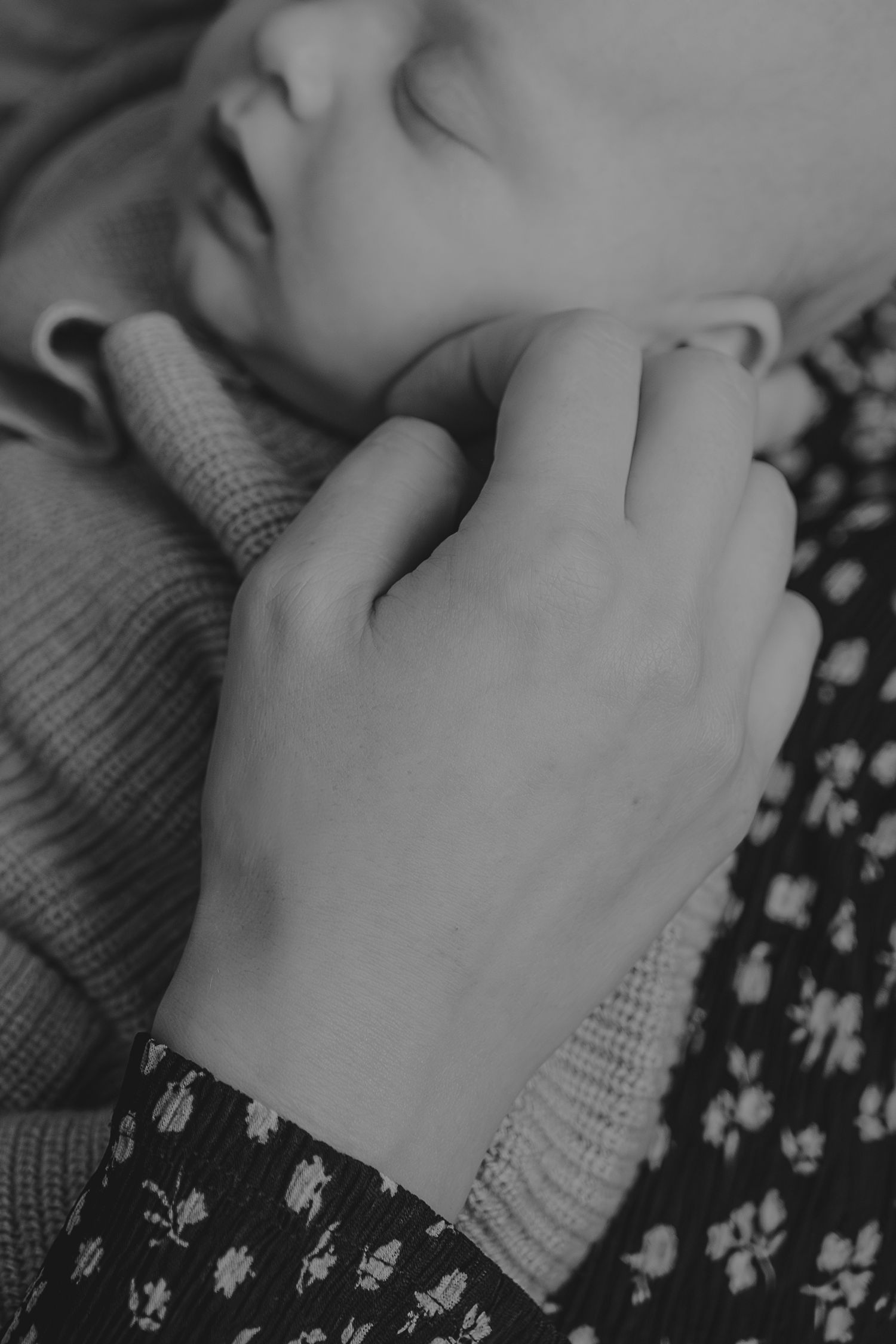 A close-up black and white image of a gentle hand touching a sleeping baby.