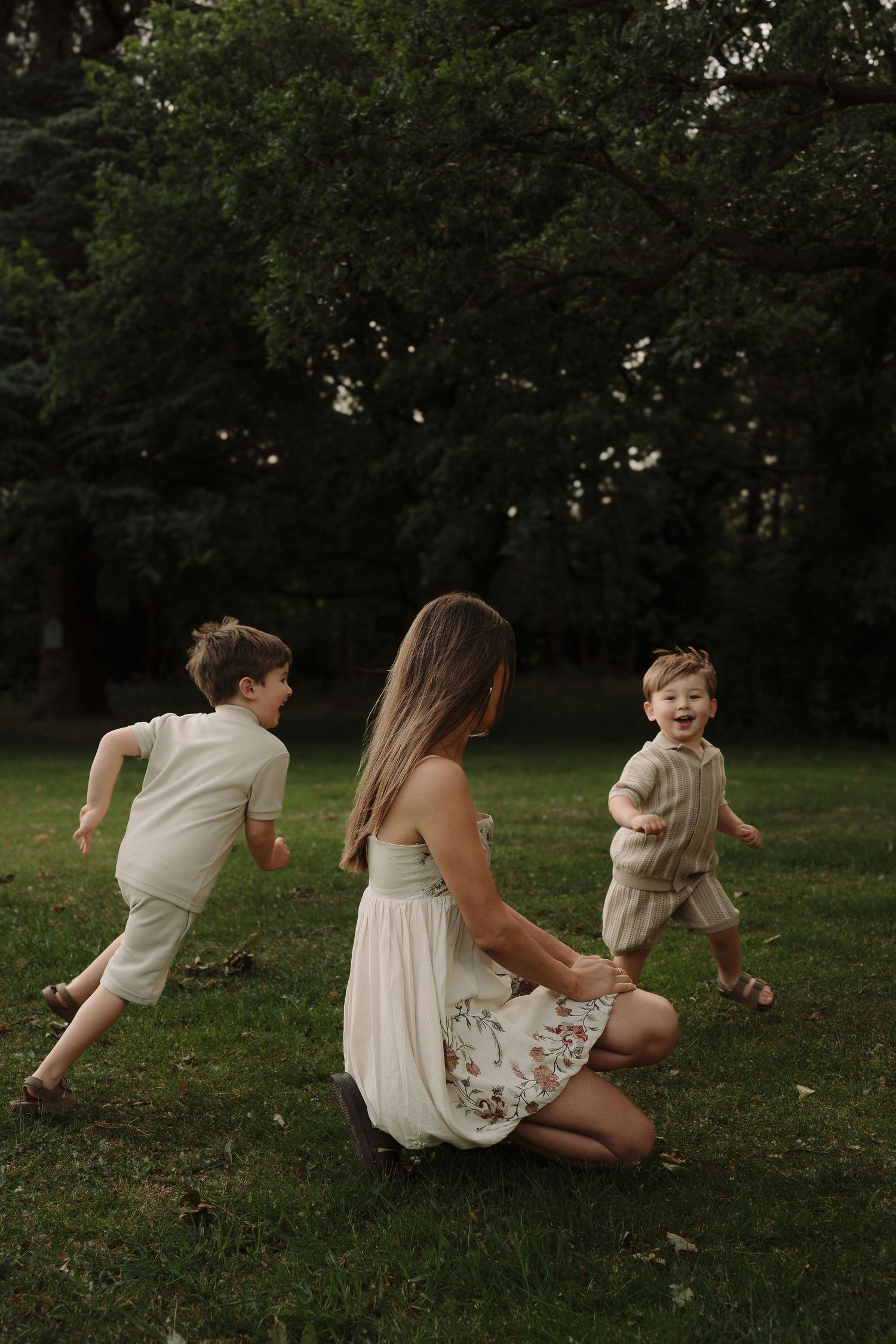Candid sequence of family members playing and rolling together on grass in white summer outfits by a Tamworth family photographer.