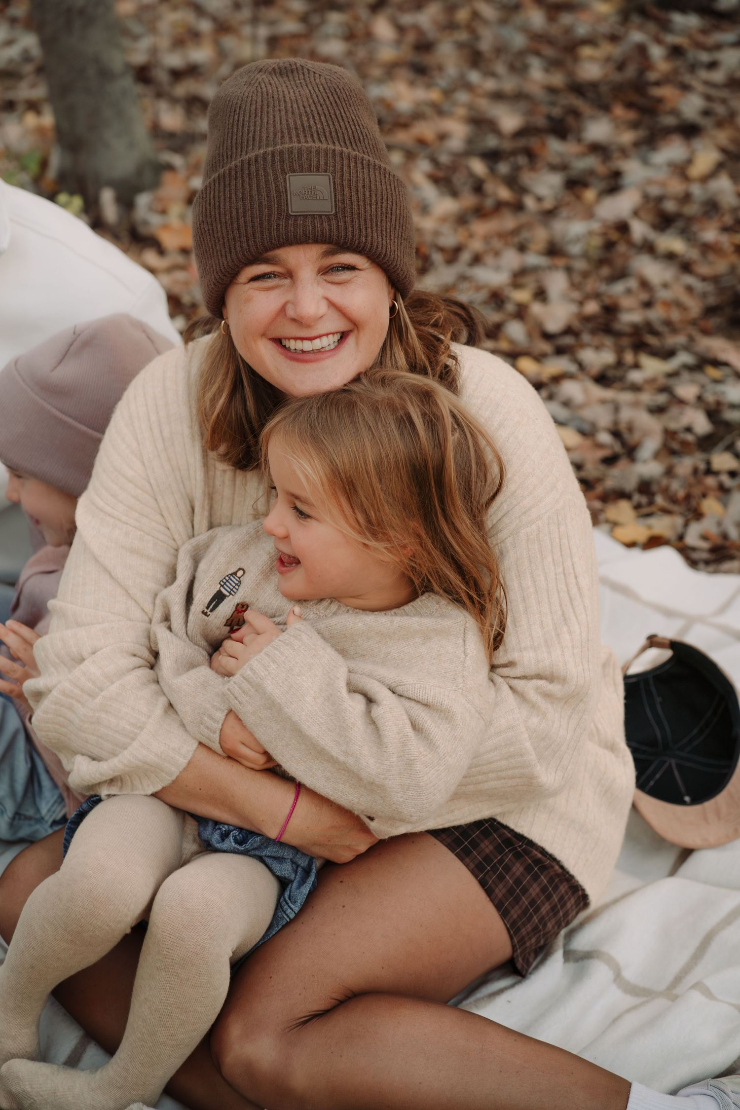 Cozy autumn family photos on fallen leaves showing warm embraces and genuine laughter.