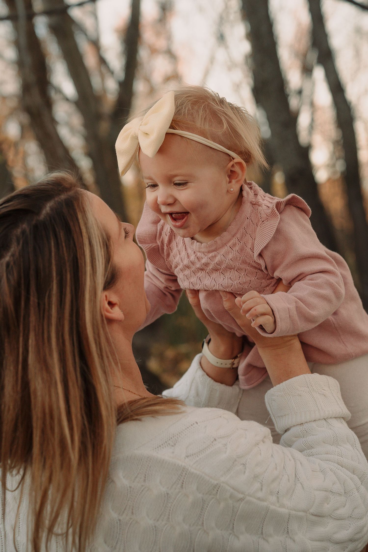 A tender moment of parent and baby sharing joyful laughter in a series of candid outdoor portraits.