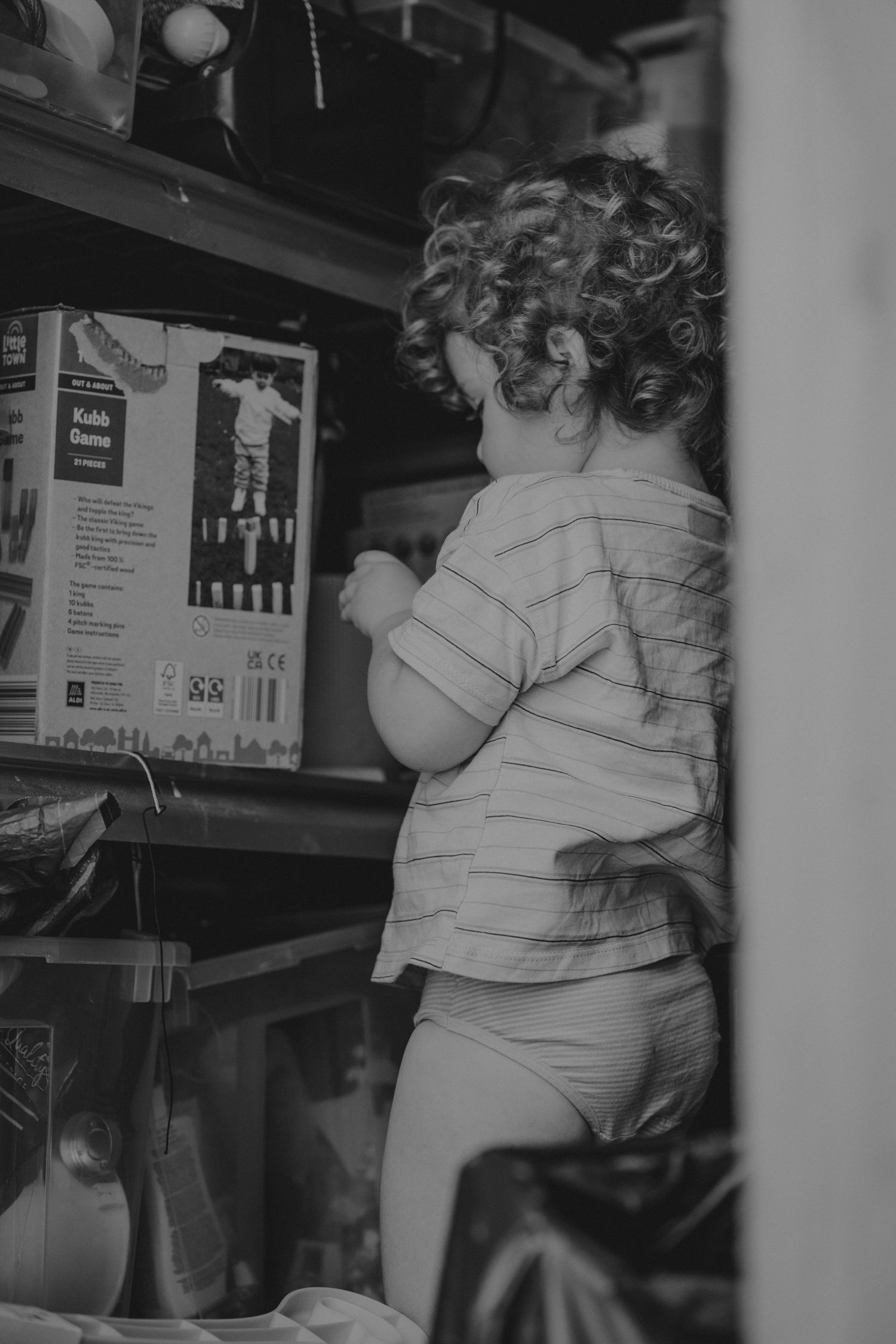 Black and white images showing a small child reaching for items on shelves.