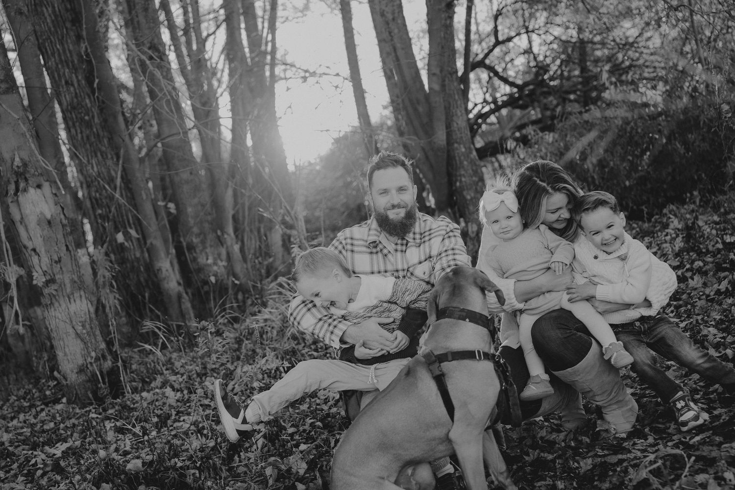 Family walking together through misty forest path in black and white.