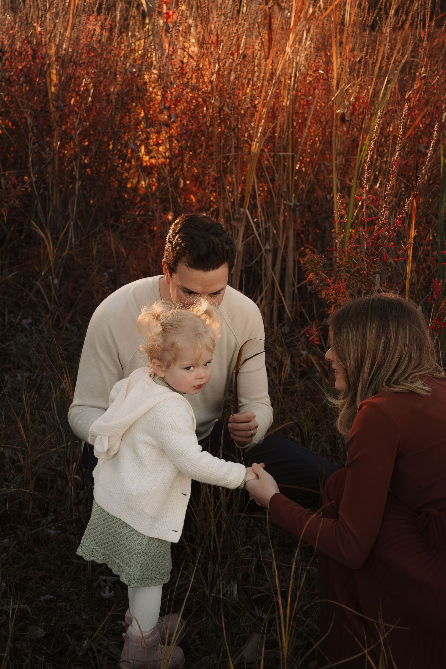 Family playing among rustic autumn foliage at sunset with warm golden tones.