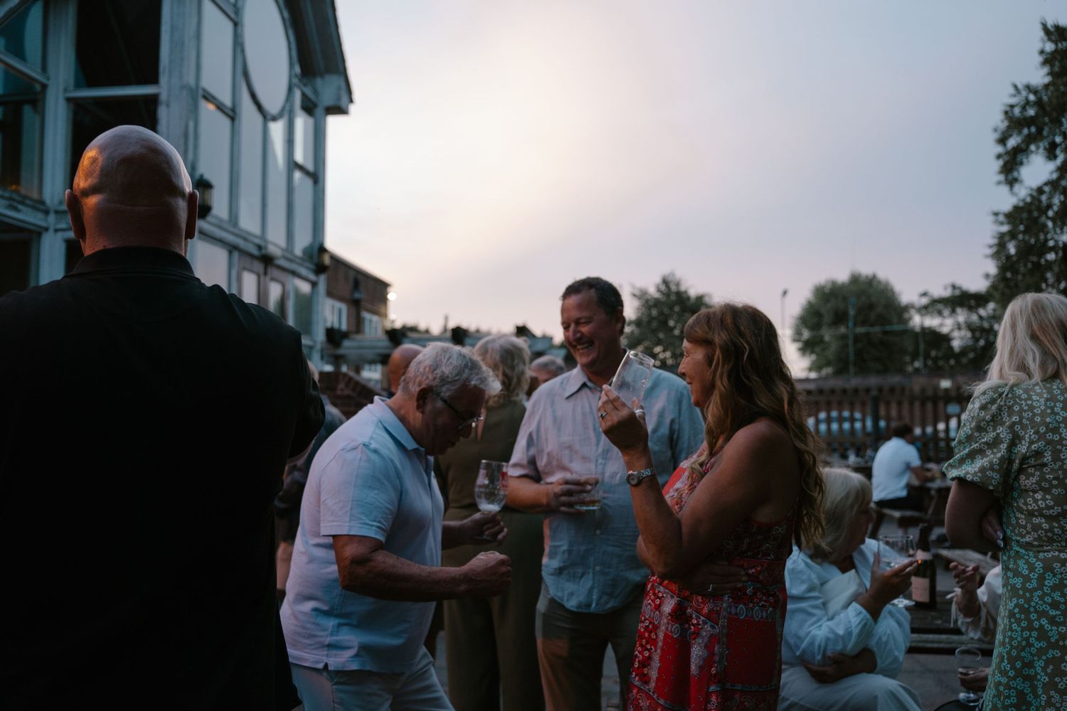 People gathering outside a white building during sunset or dusk.