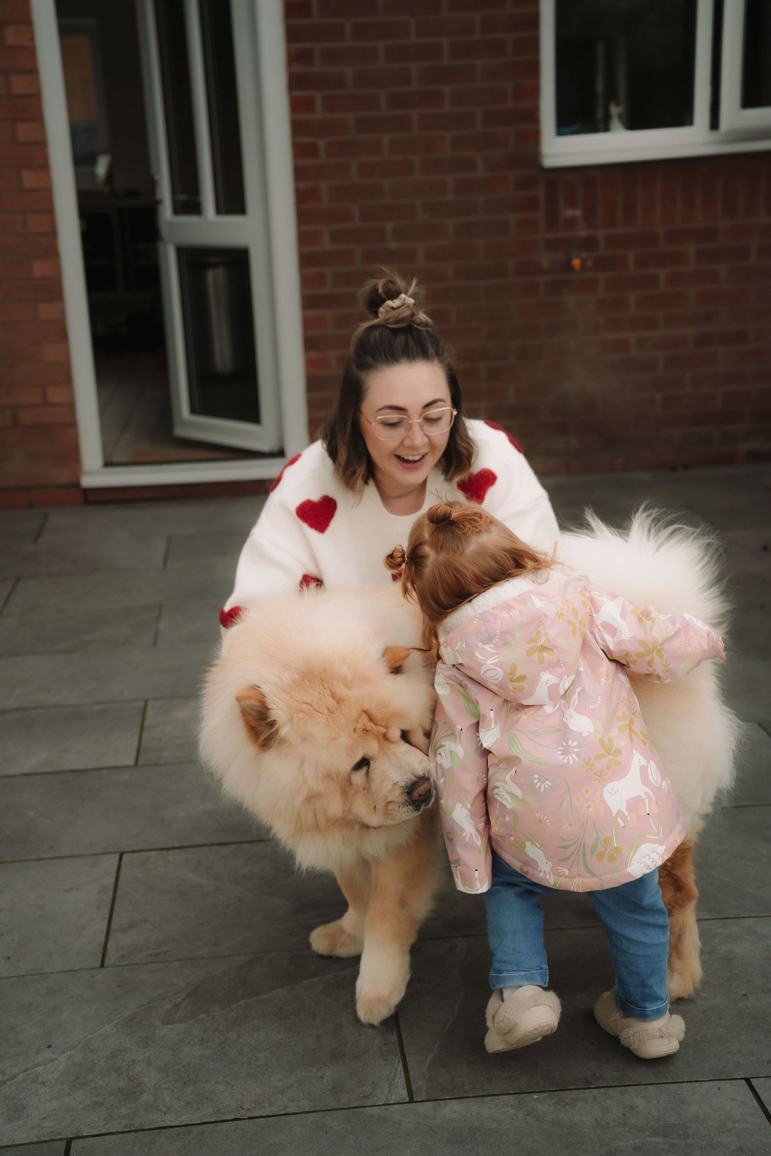 A sequence of photos showing a person petting and playing with a fluffy cream-colored dog wearing a pink dress.