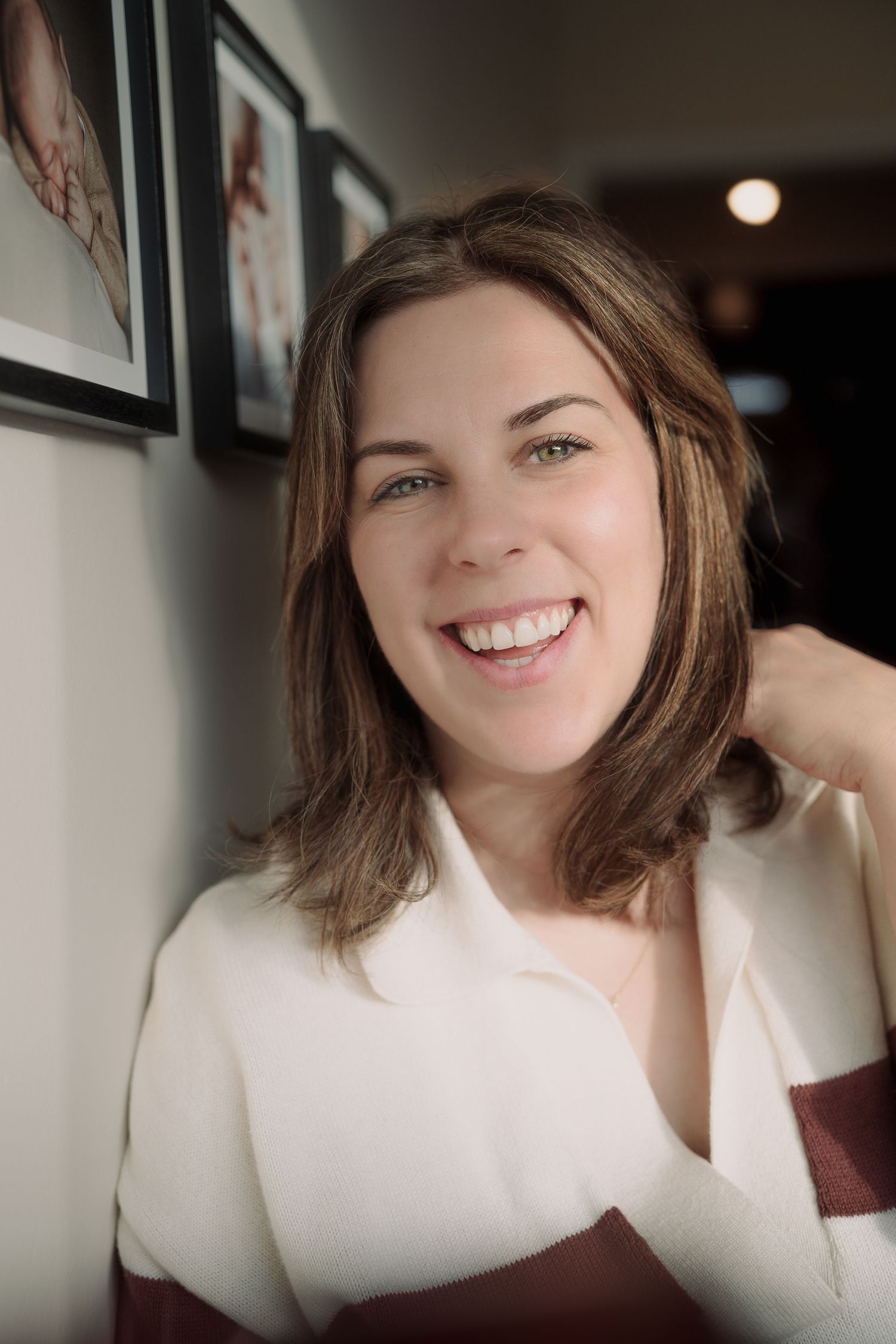 woman wearing a white and red striped jumper smiling at the camera with hand up by Tamworth family photographer.