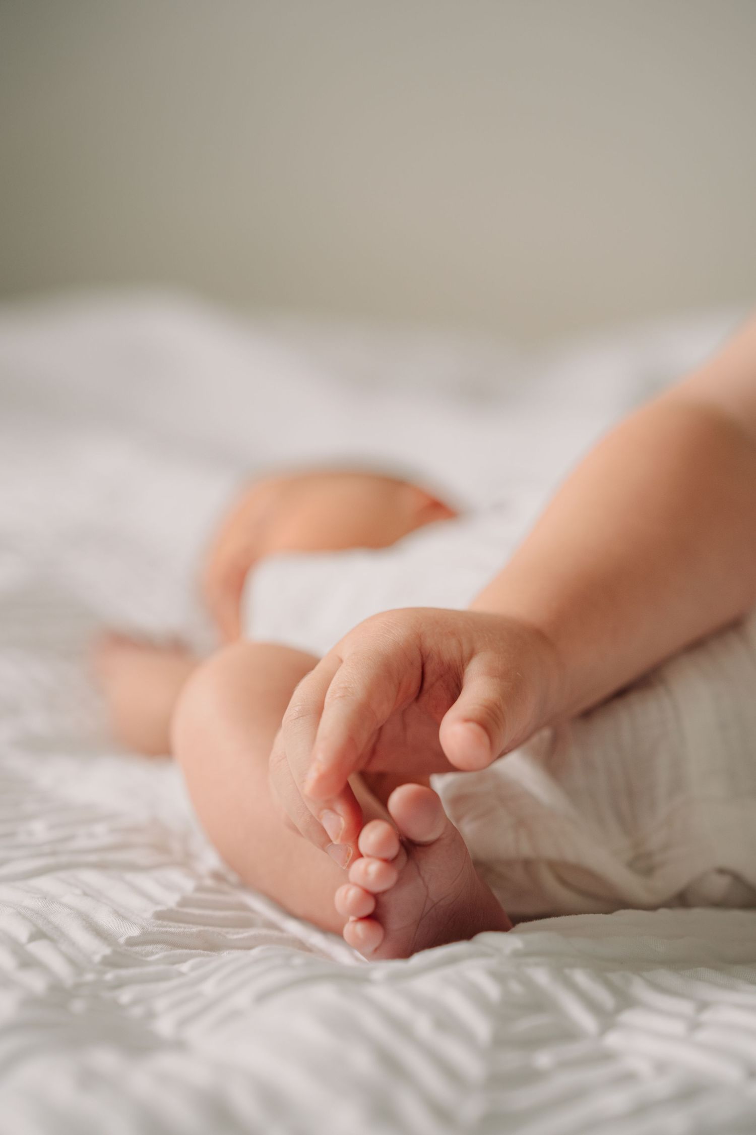 Delicate baby feet resting on white textured bedding.