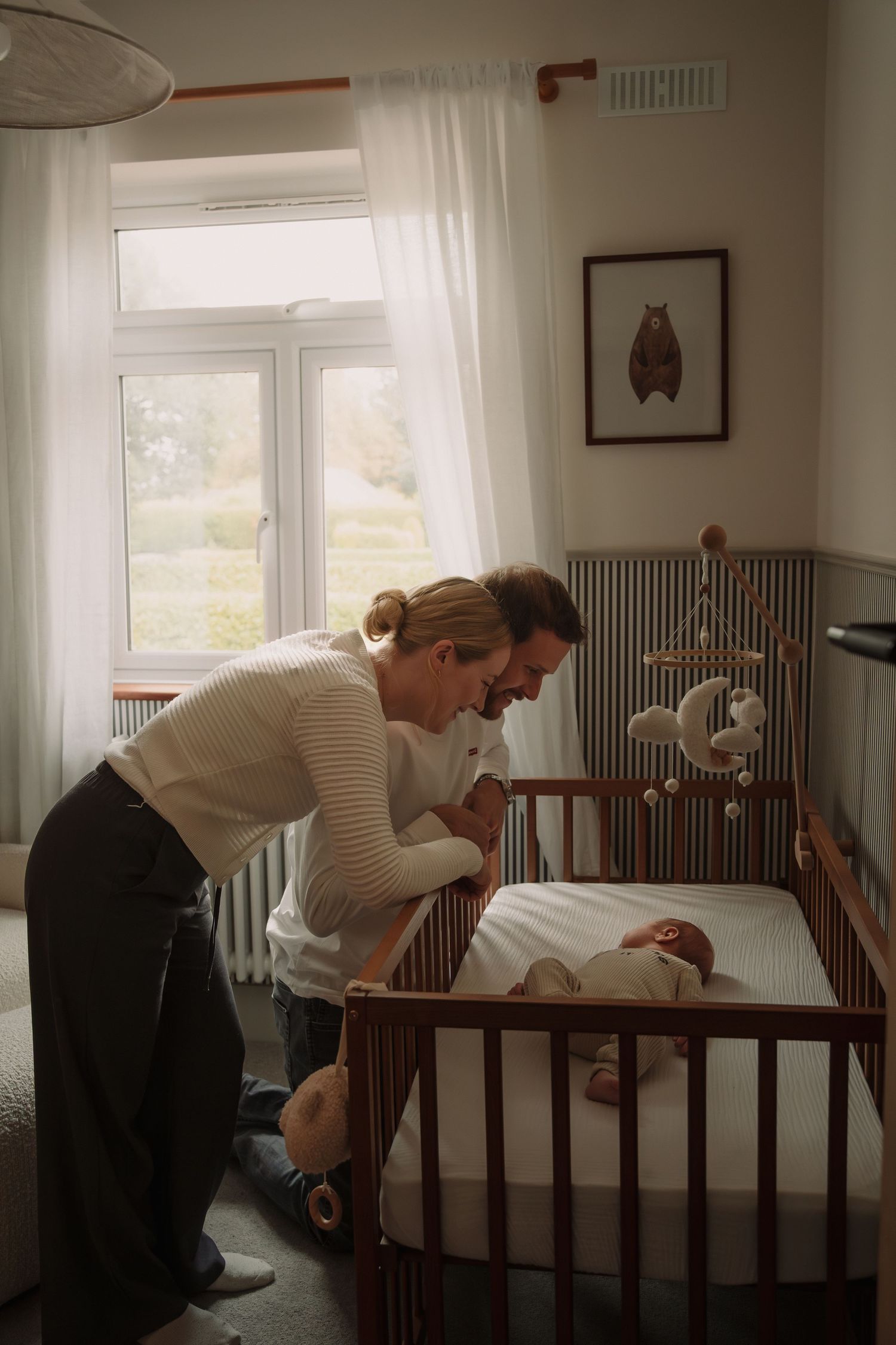 A series of three photos showing a parent leaning over a wooden crib in a bright nursery room.