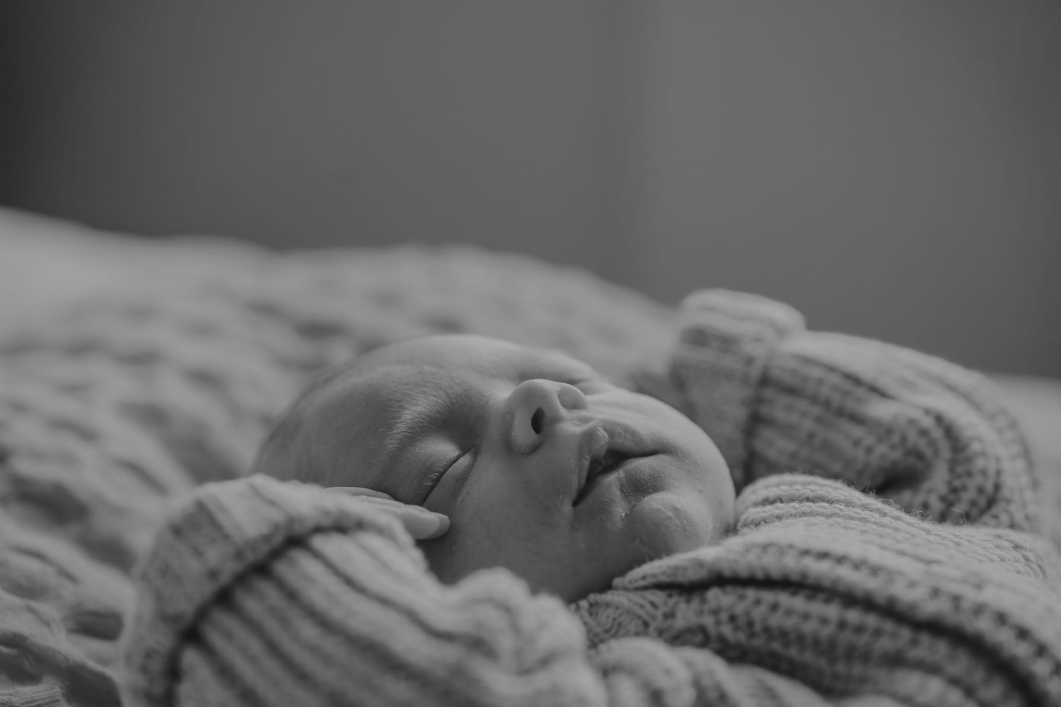 Peaceful black and white portrait of sleeping infant on textured blanket.
