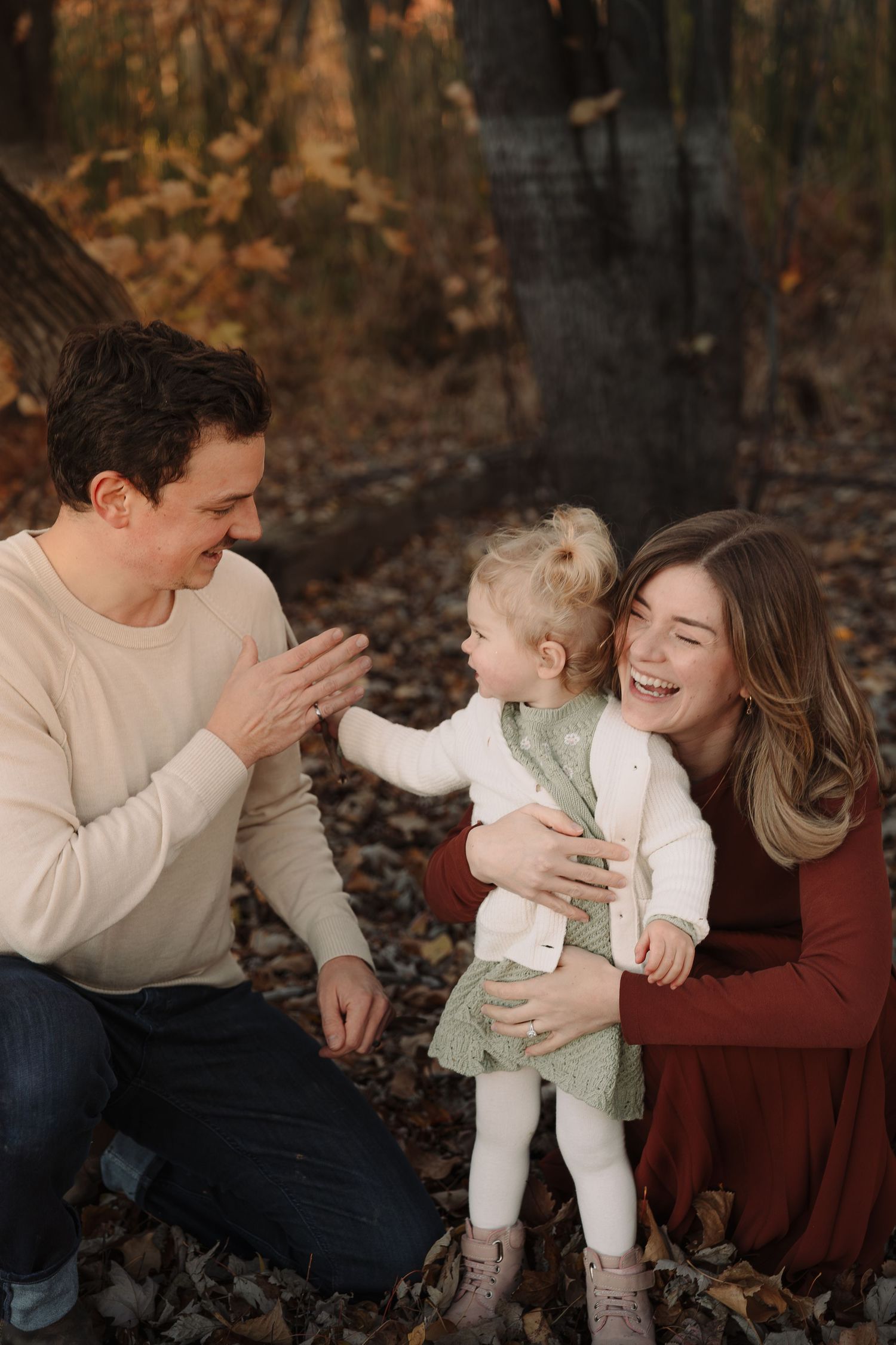 Candid family moments captured in autumn leaves with natural laughter.