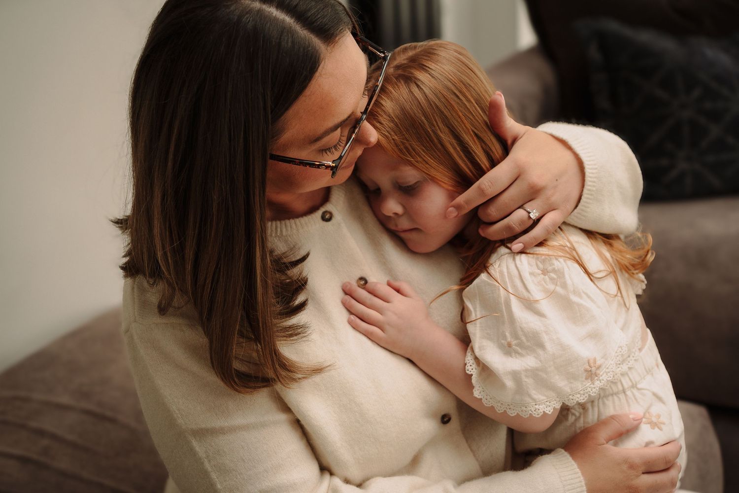 Intimate family portrait with soft lighting against neutral background.