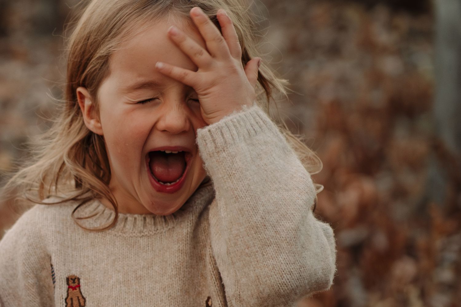 Joyful autumn outdoor photoshoot showing playful expressions and warm sweaters.