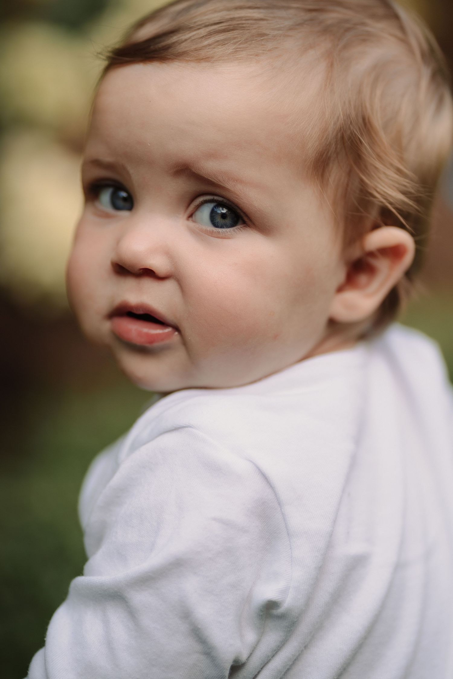 baby looking over shoulder with pouty face during an outdoor family photoshoot in Tamworth.