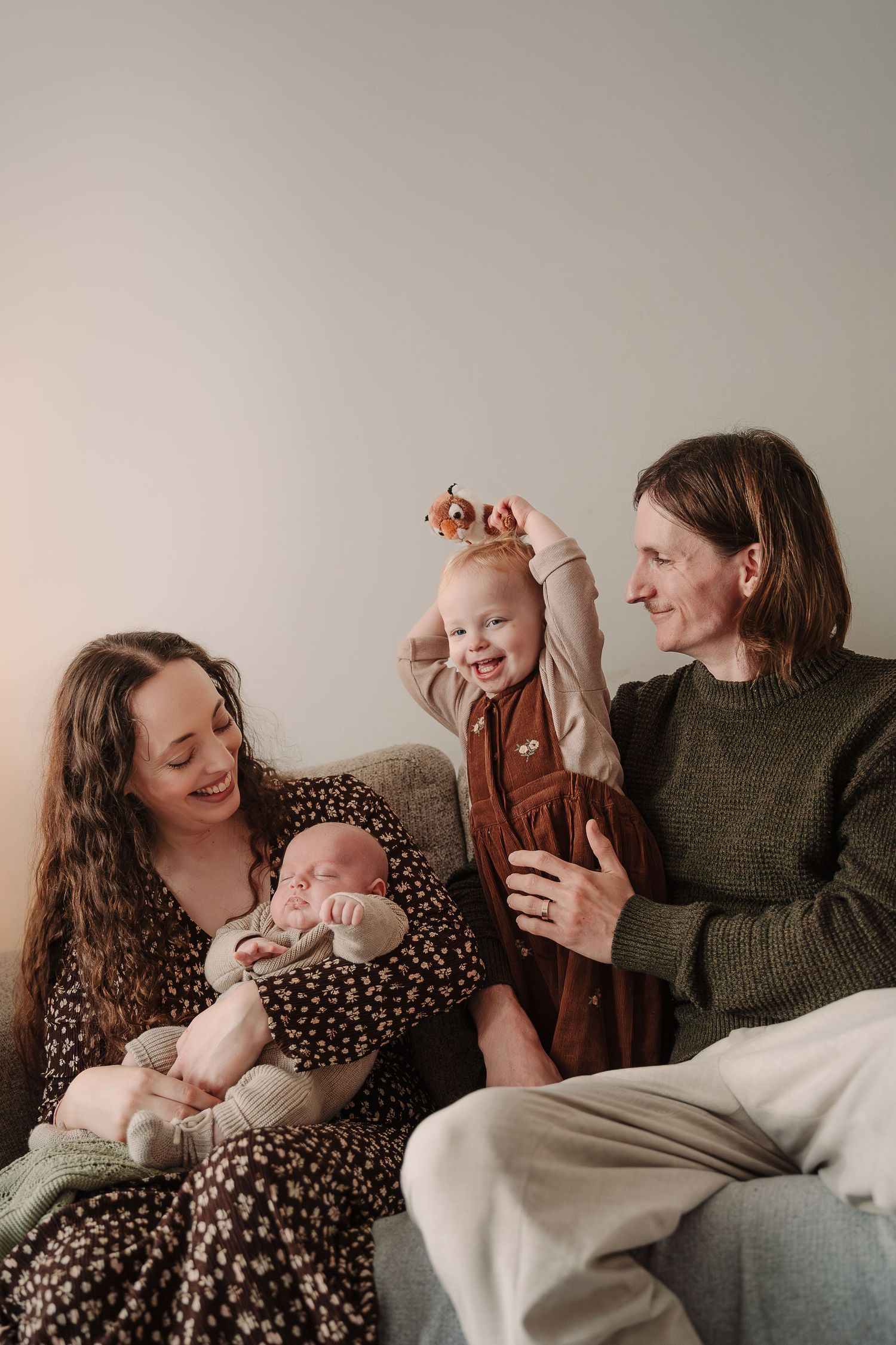 A joyful family moment on a couch with a baby and toddler.