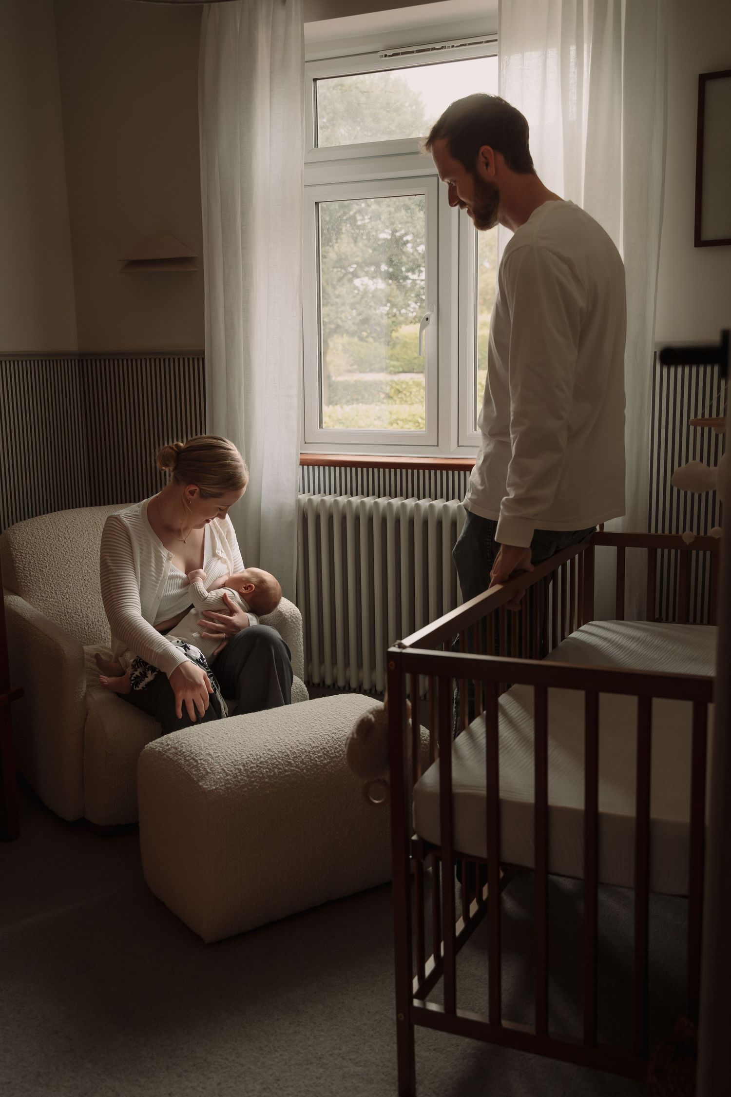A series of moody photographs showing tender moments between parent and baby in a softly lit nursery room.