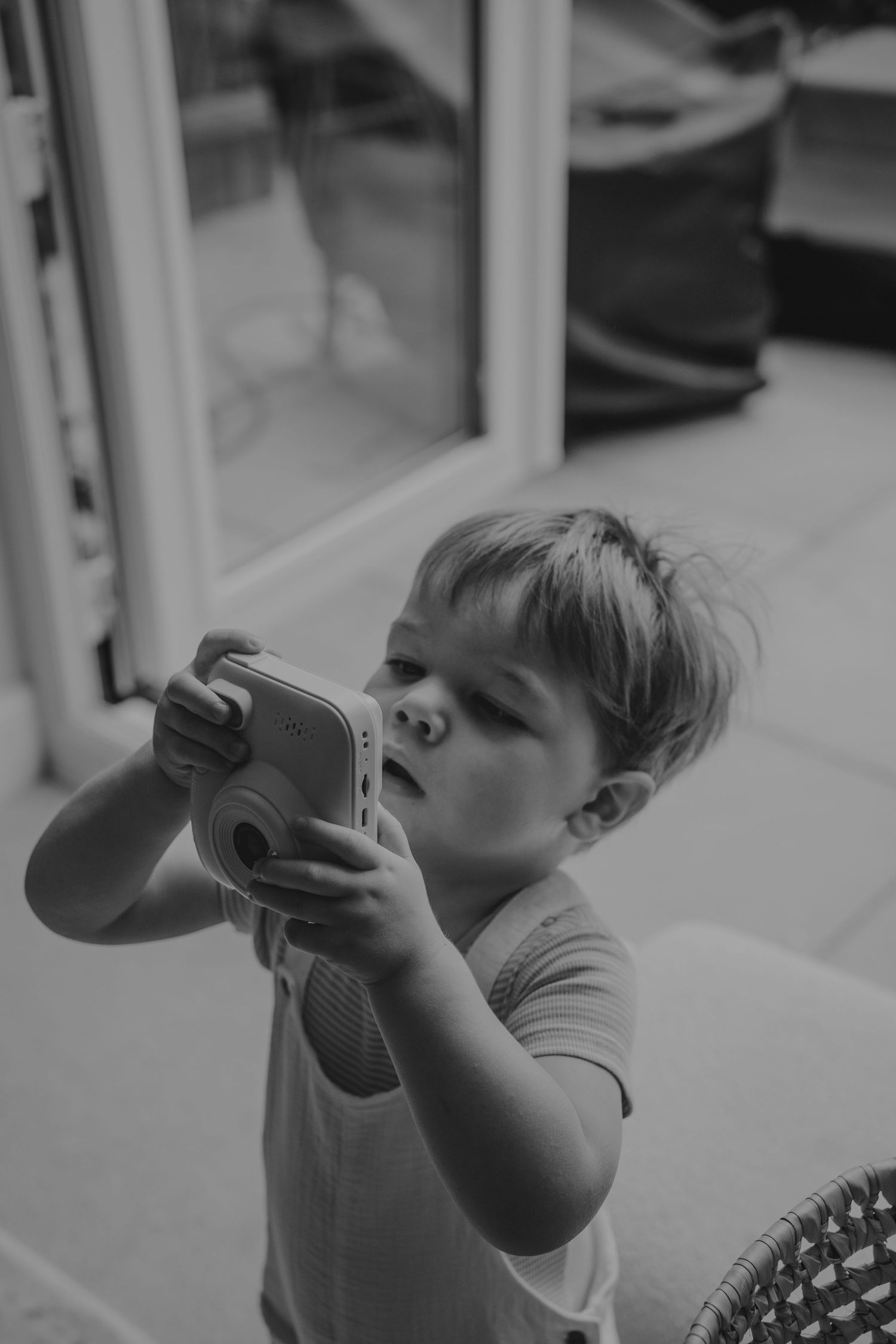 Child playing with toy microphone in black and white photography.