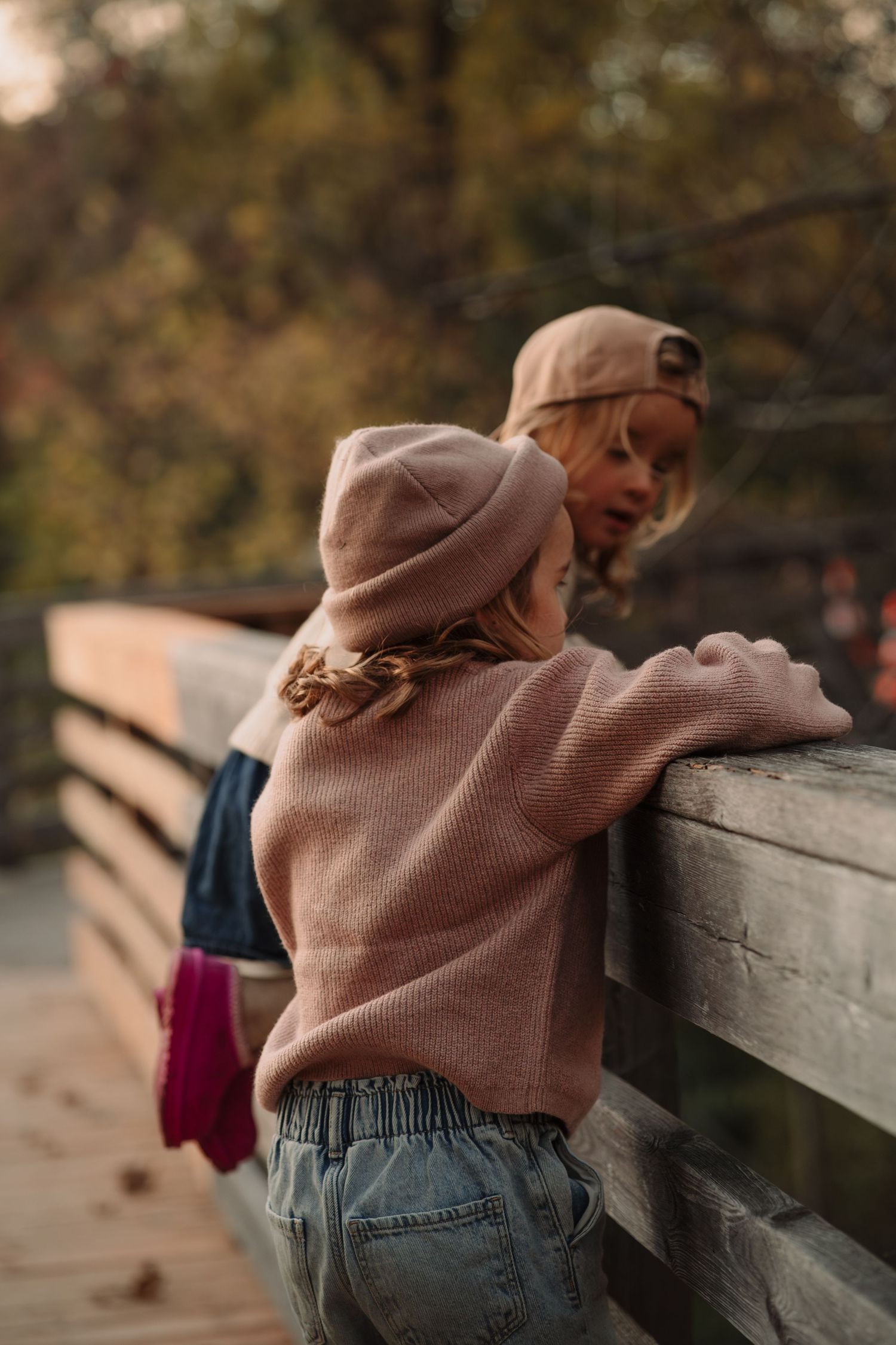 Close-up details of casual autumn outfit with jeans and sweater against wooden railing.
