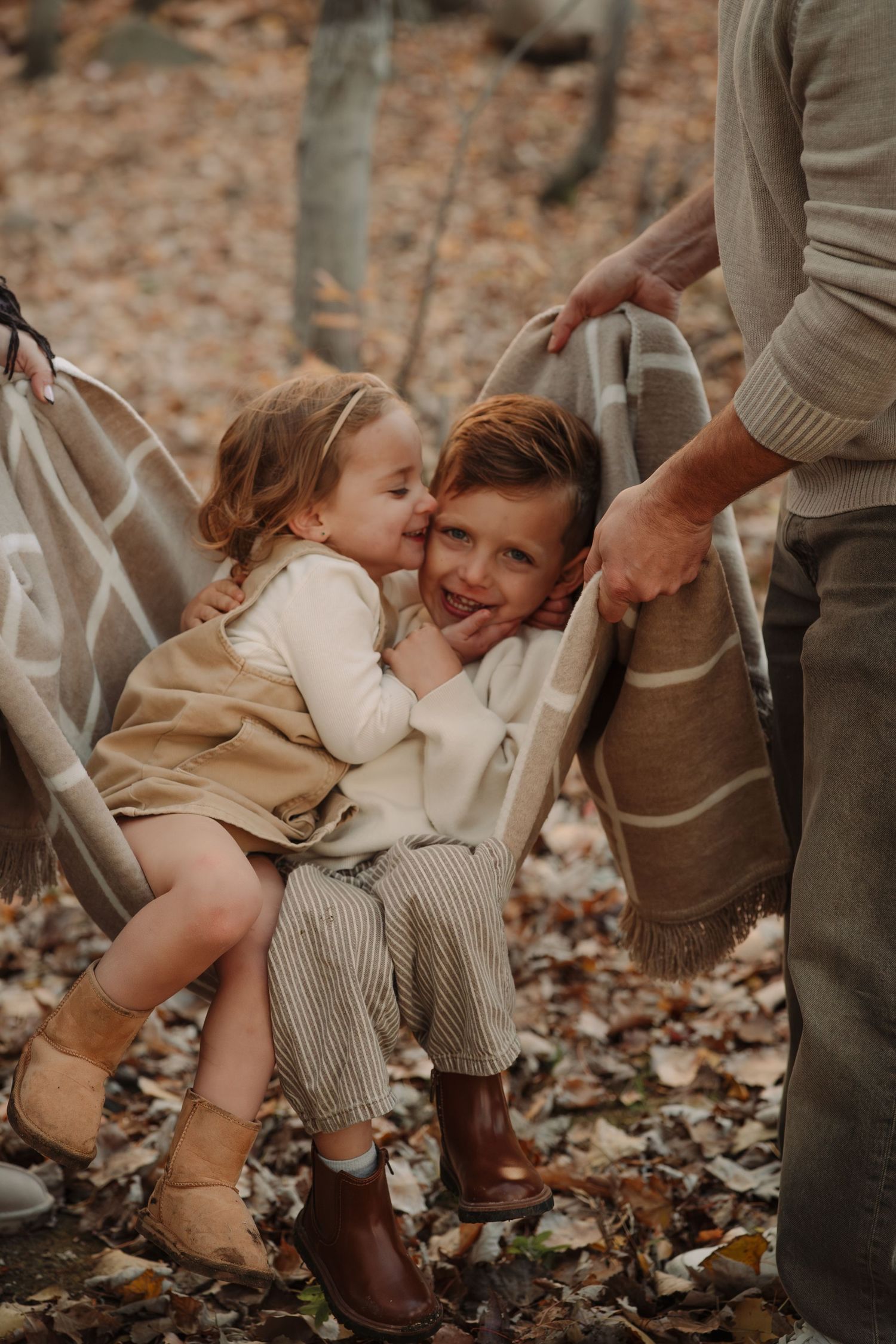 Girl kissing boy swinging in a blanket swing during an outdoor family session in Tamworth.