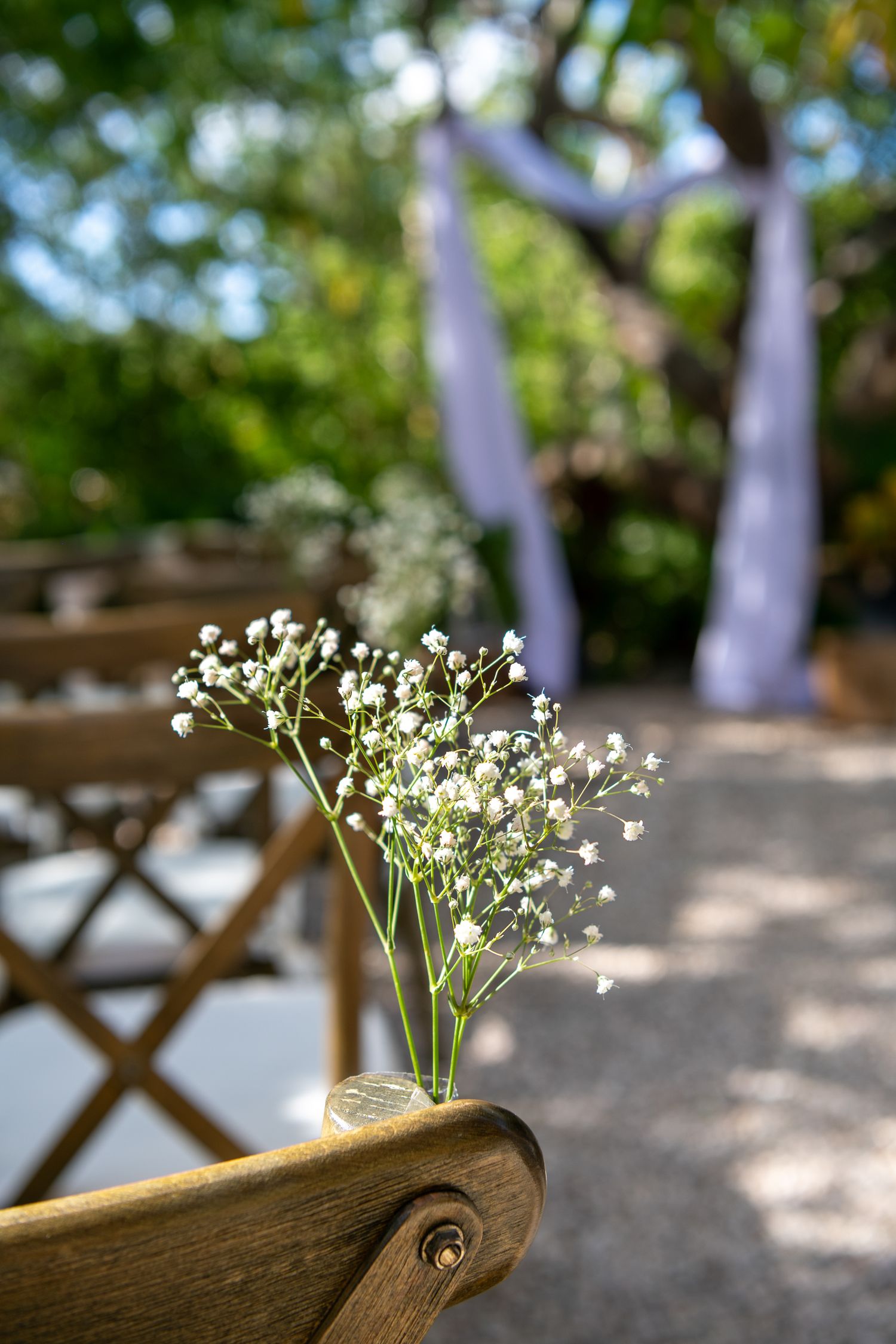 Delicate white baby's breath flowers arranged in rustic wooden holders create an elegant outdoor wedding decoration.