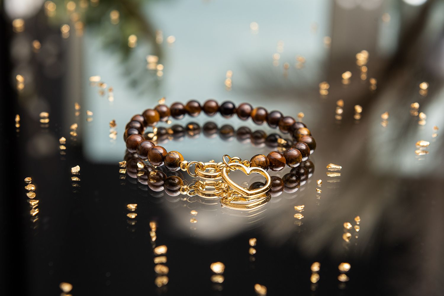 Golden wedding rings and beaded jewelry displayed with sparkling bokeh lights in a romantic setting.