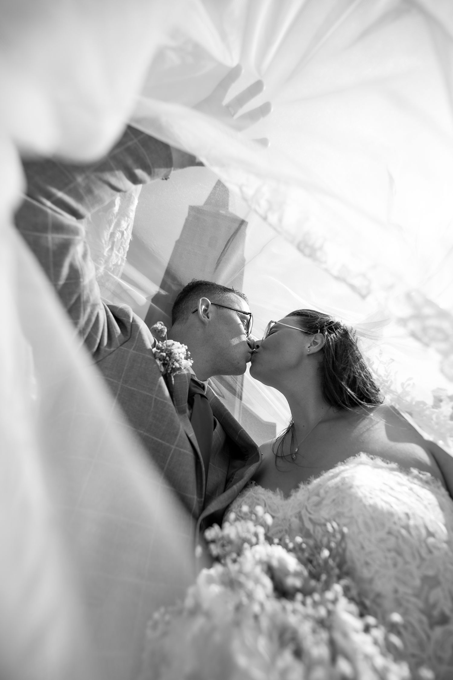 Black and white wedding photo sequence showing a romantic kiss between newlyweds in formal attire.