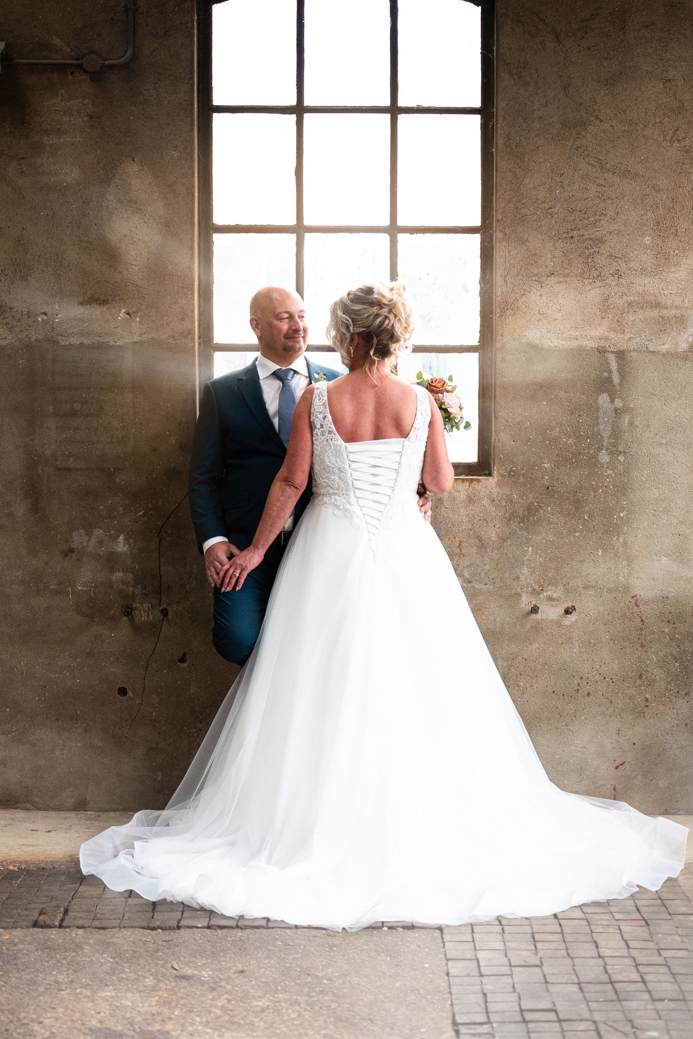 A romantic wedding photo sequence showing a bride in a flowing white gown and groom walking together in an industrial space.