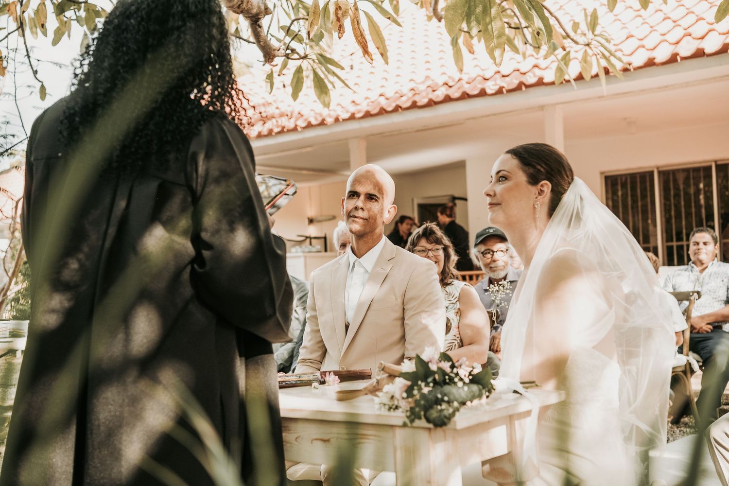 A bride and groom share a joyful moment during their outdoor wedding ceremony under autumn foliage.
