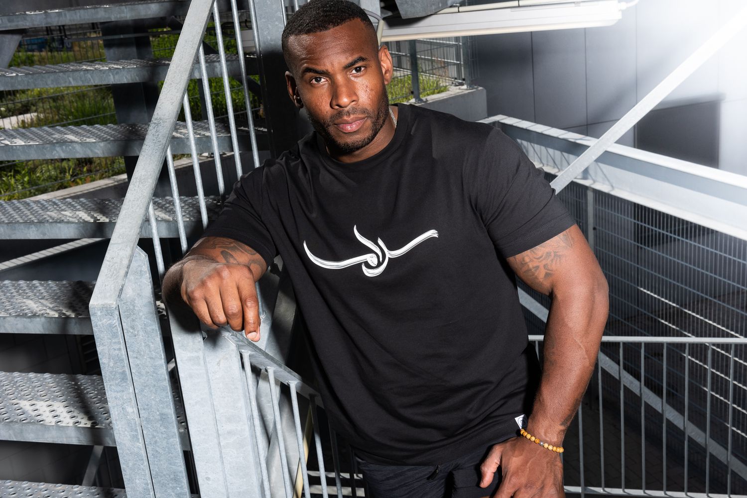 Athletic person in black t-shirt posing on modern staircase in dynamic photo series.
