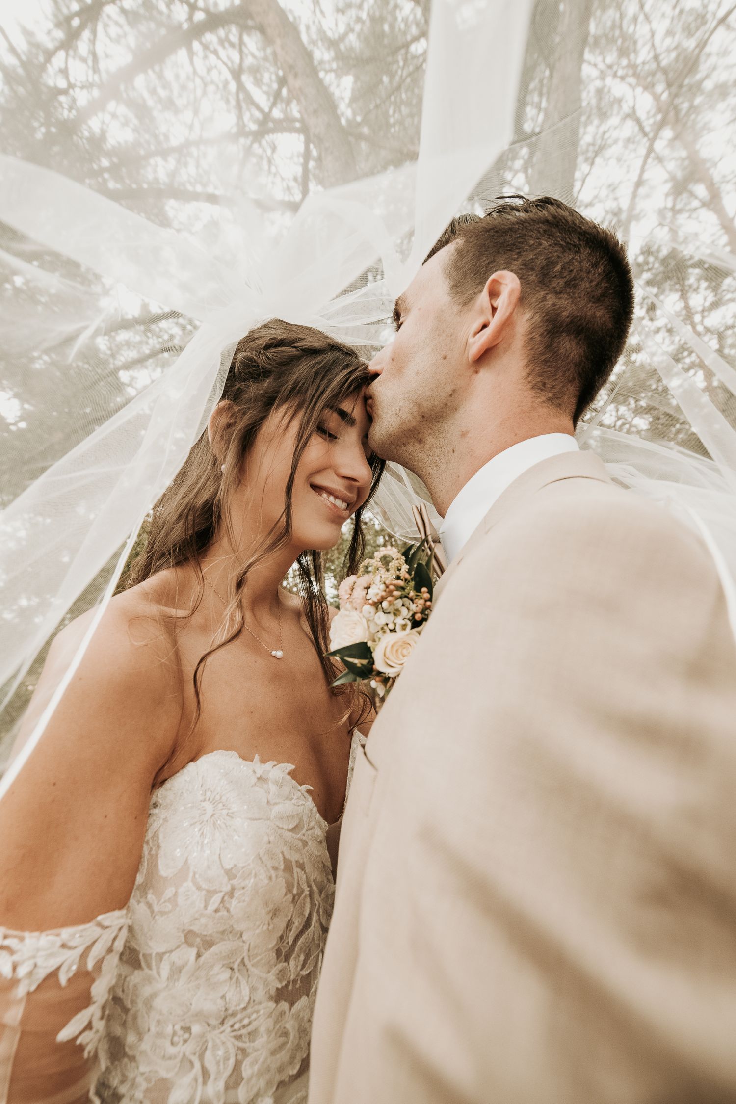 Romantic wedding couple sharing intimate moments in a dreamy outdoor setting with soft natural lighting.