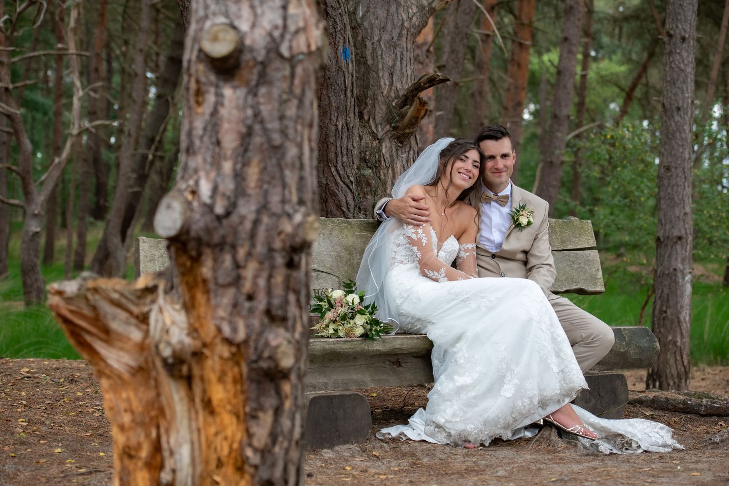A joyful wedding photo session in a serene wooded outdoor setting with tall trees and natural lighting.