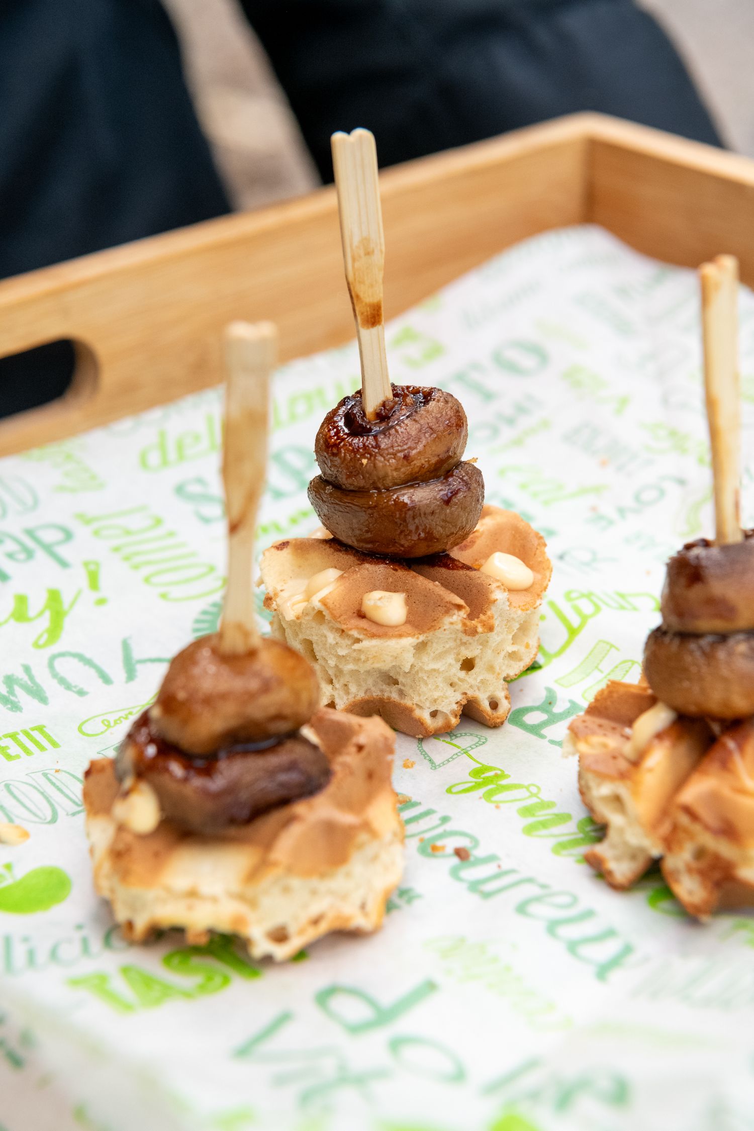 Close-up sequence of small gourmet appetizers with mushrooms and sauce on white paper with green text.