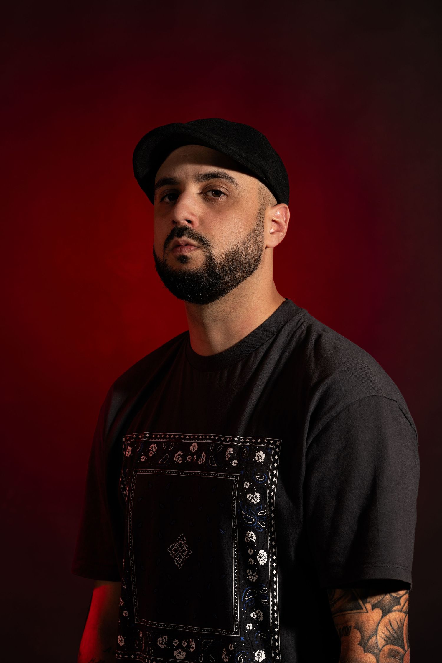 Artistic portrait series against dark red backdrop showing person in black clothing and hat with dramatic lighting.