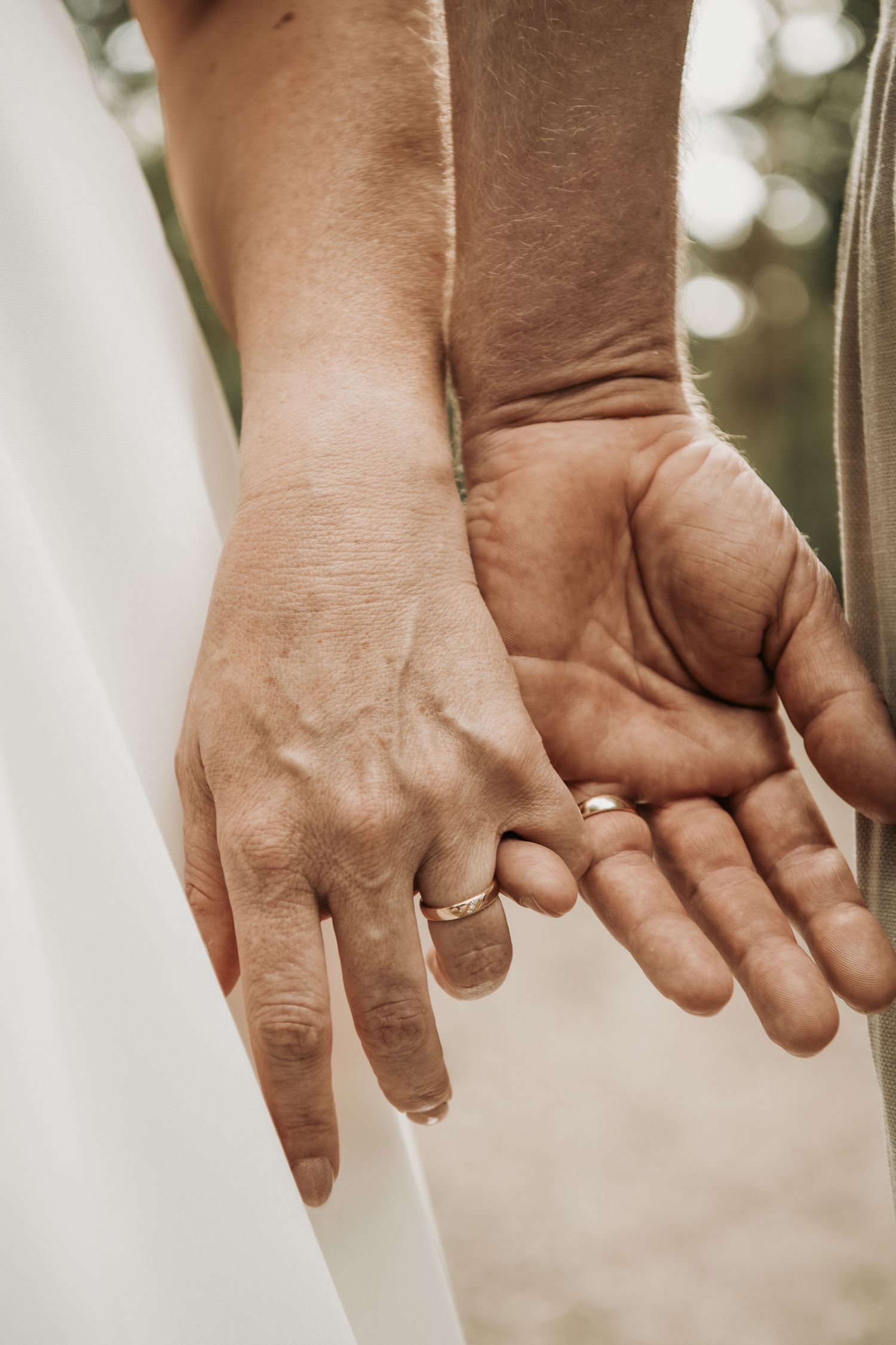 Close-up detail of two hands gently touching during a wedding ceremony.