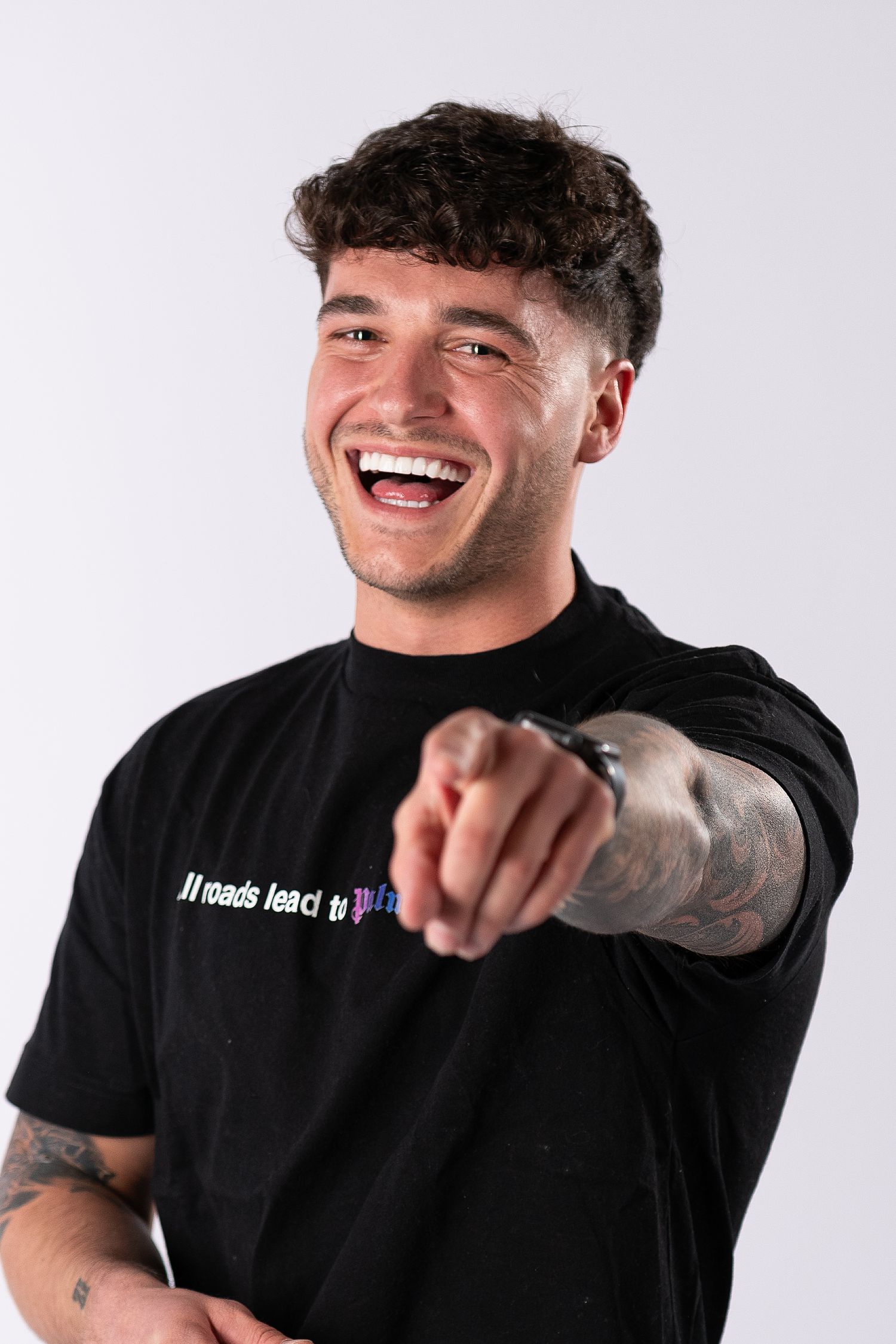 Young man in black t-shirt laughing and pointing at camera against white background in three-photo collage.