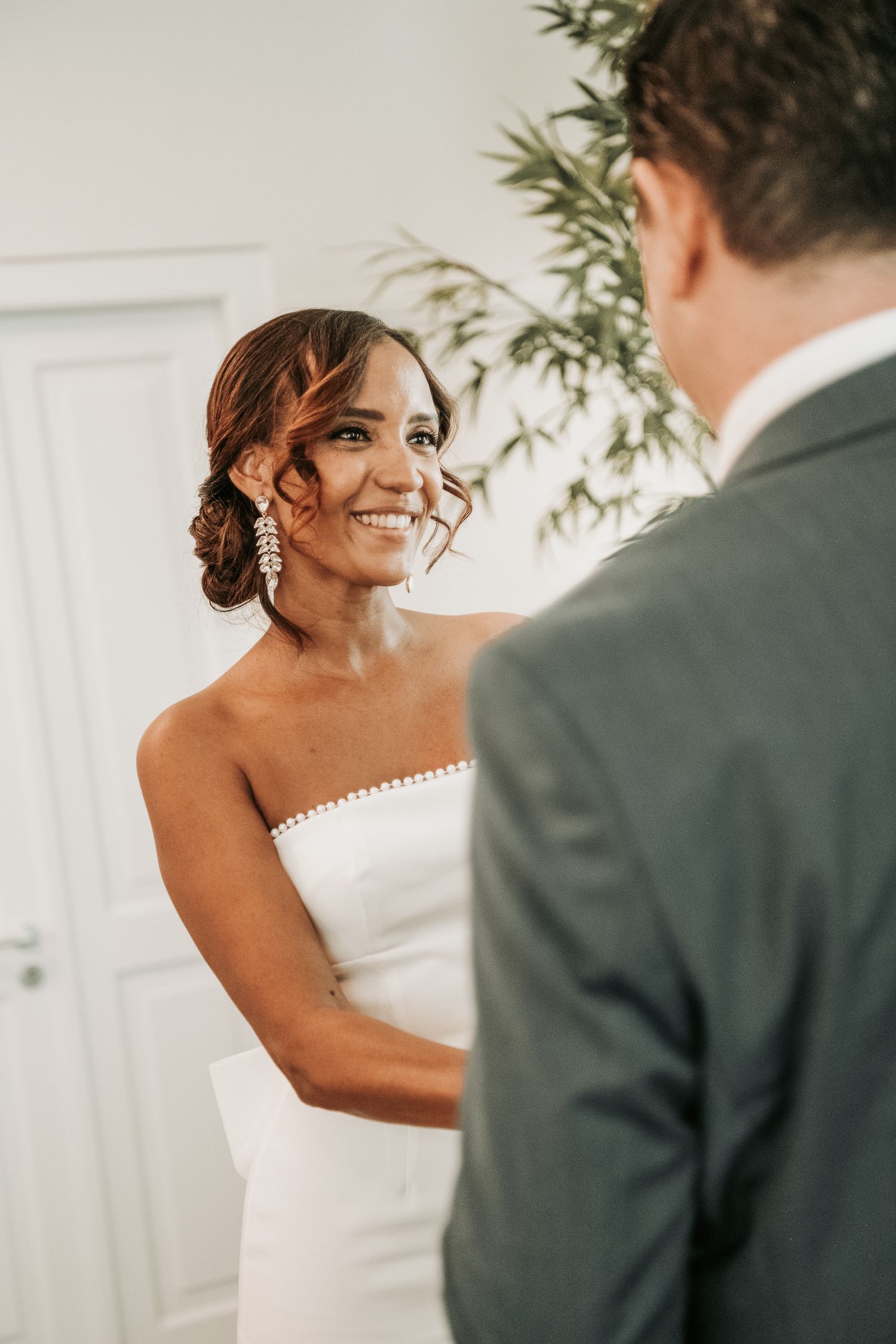 A joyful moment captured during a wedding ceremony with the bride in a white strapless gown and elegant updo hairstyle.