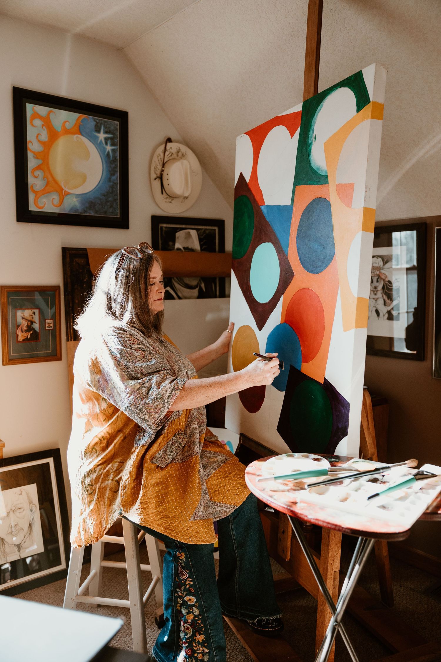 Artist working on large colorful abstract painting in home studio space.