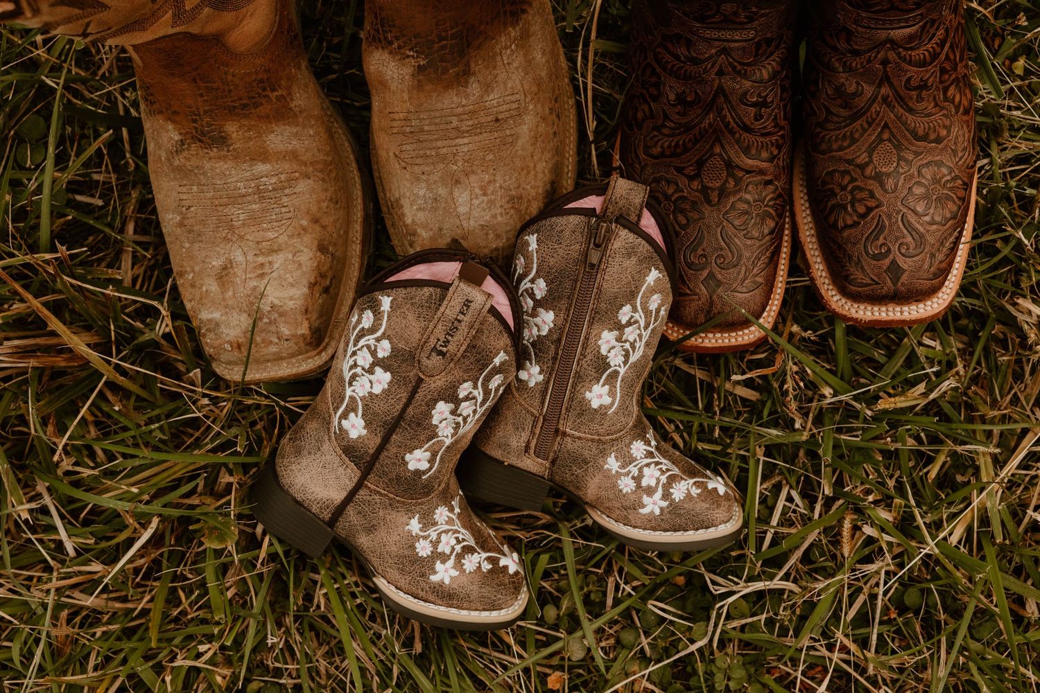 Close-up of decorative boots arranged on grass showing floral patterns.