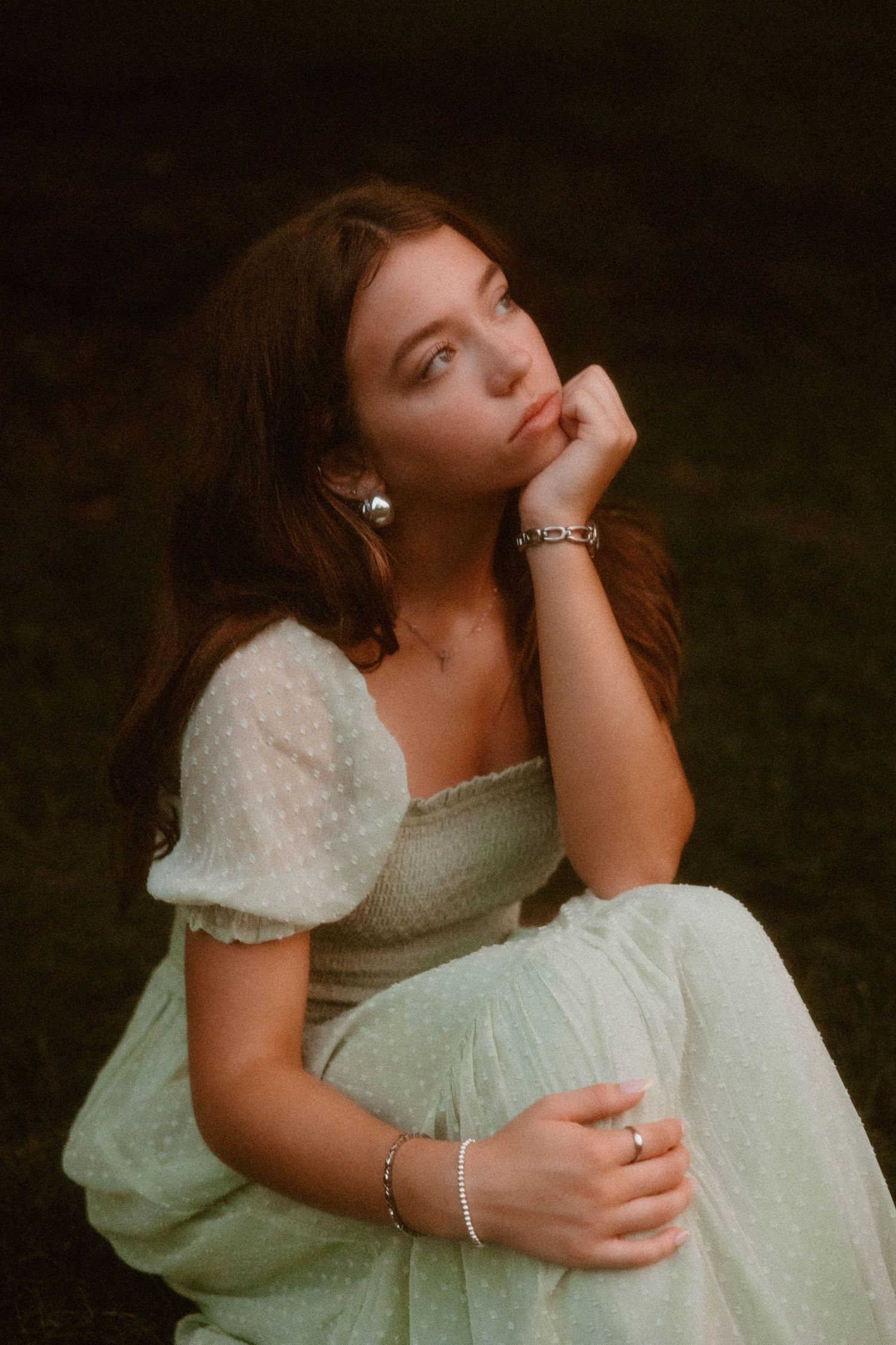 A dreamy portrait of someone in a vintage-style white dress against a dark background.