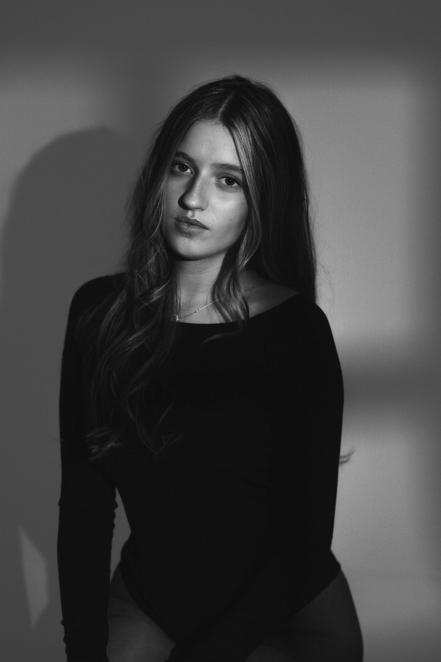 Dramatic black and white portrait of woman in black top with long hair.