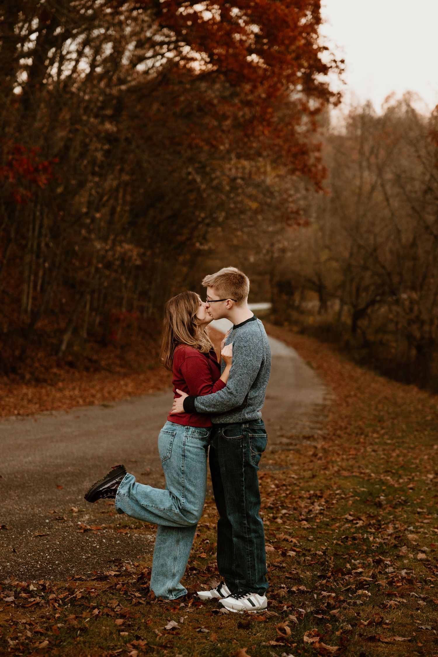 A romantic autumn scene on a tree-lined path with warm fall colors and fallen leaves on the ground.